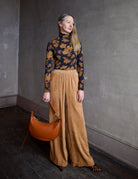 image of a woman wearing the Ulla Johnson Aurelia turtleneck, forte forte matte corduroy pants, Ulla Johnson Twyla handbag and Polline Pumps