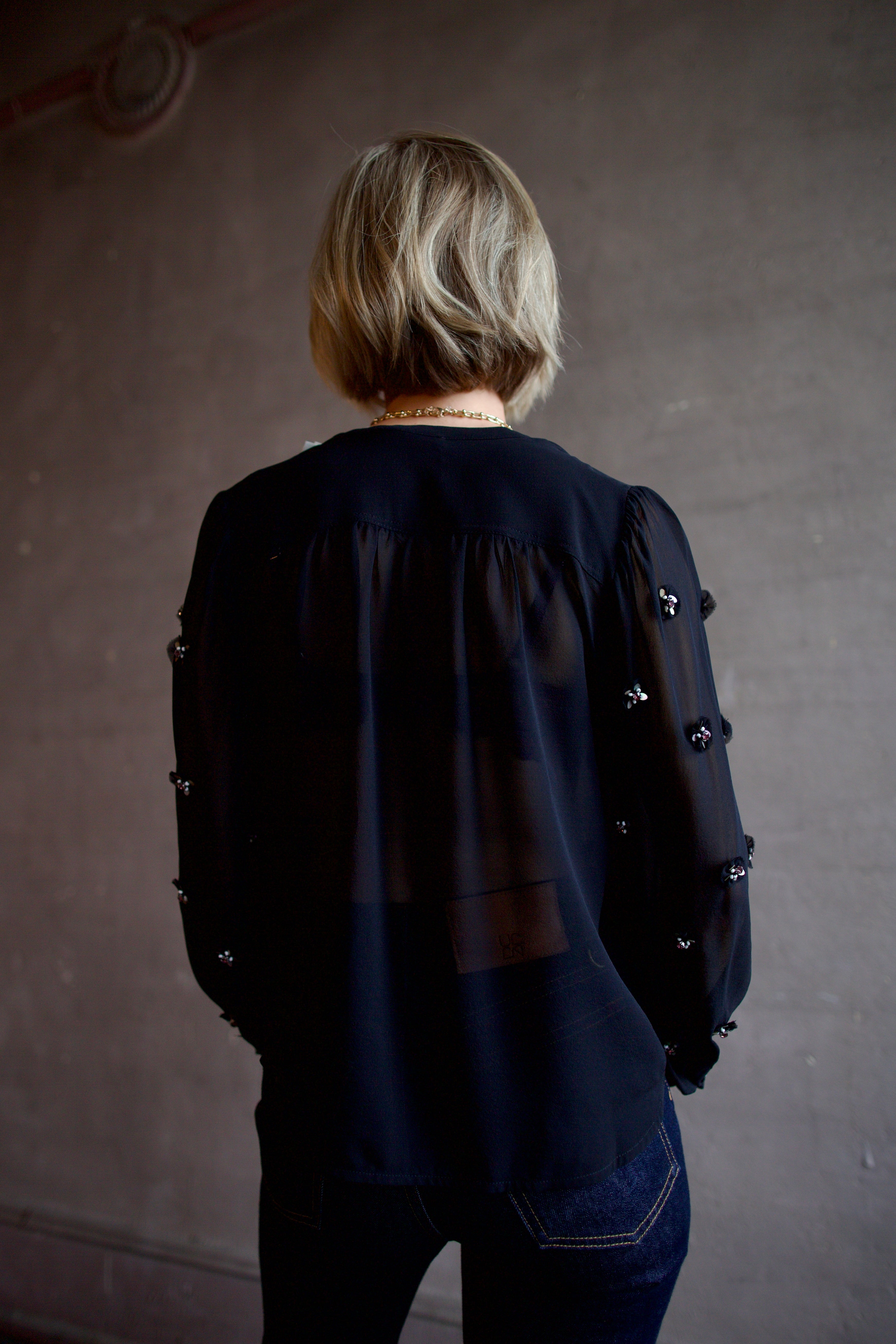Image of woman wearing luxury designer Ulla Johnson Bea black sheer silk blouse in a button-front and embellishments at front