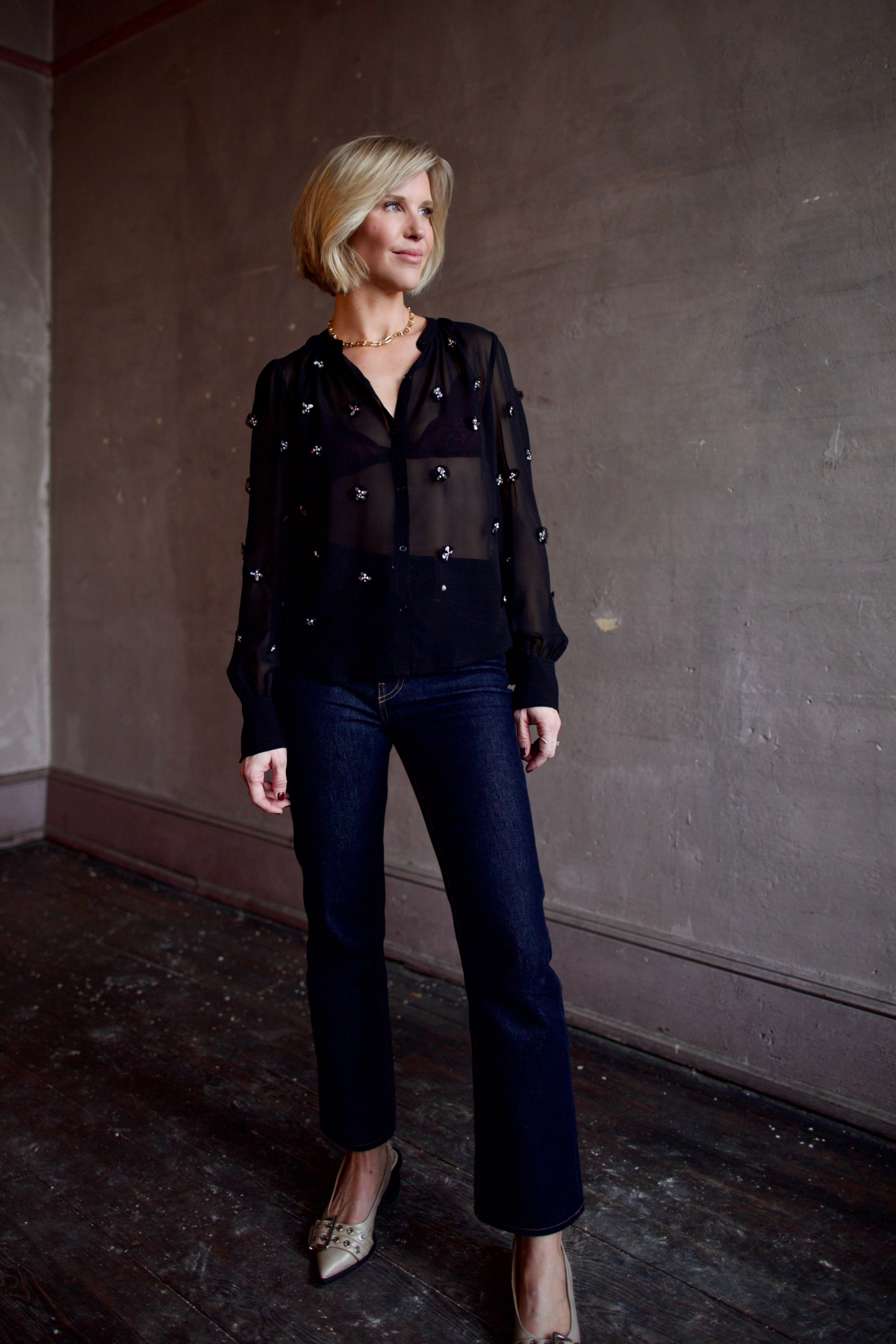 Image of woman wearing luxury designer Ulla Johnson Bea black sheer silk blouse in a button-front and embellishments on front and sleeves