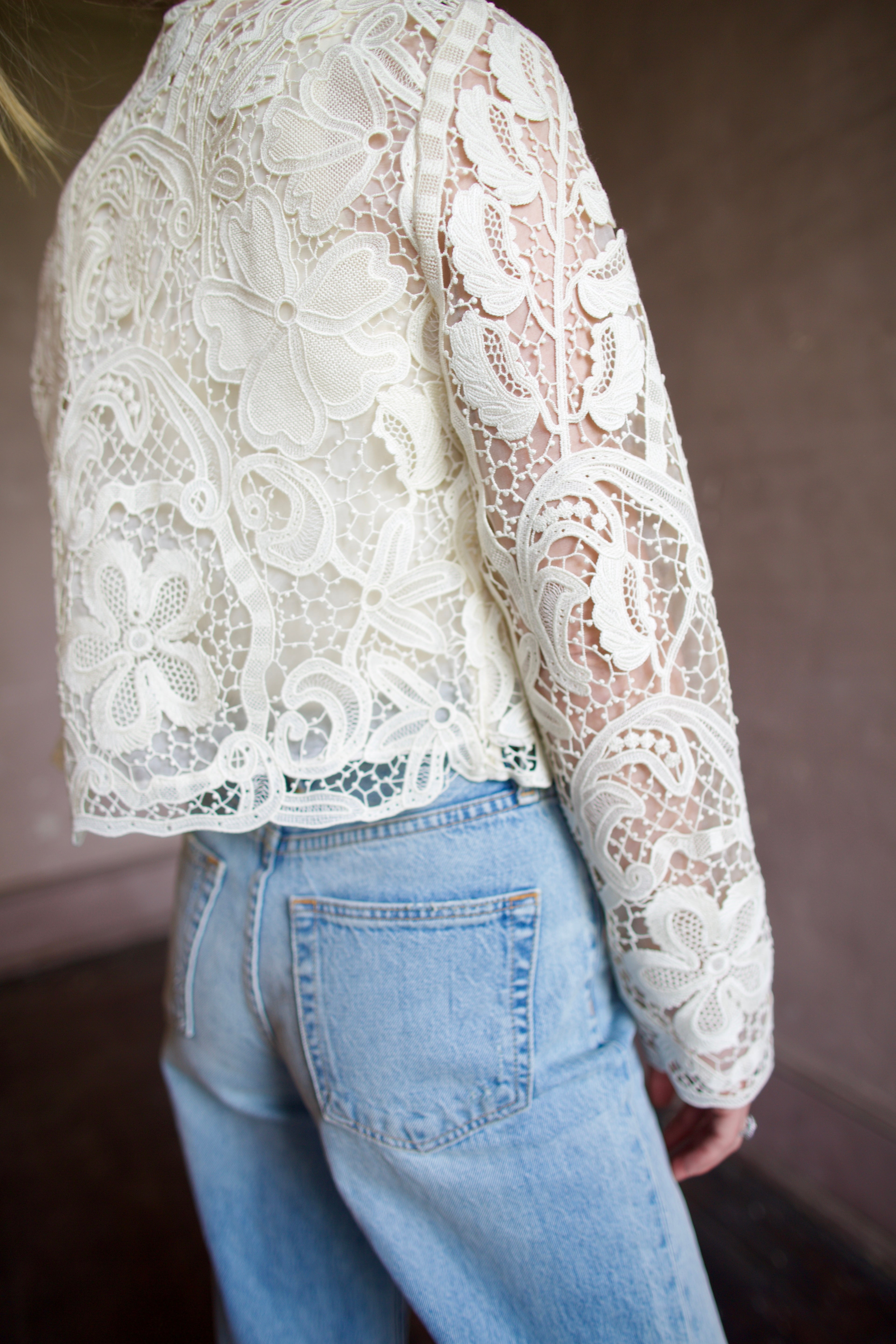 Model wearing light-weight designer jacket. This sophisticated button down jacket features an elegant embroidered floral design.