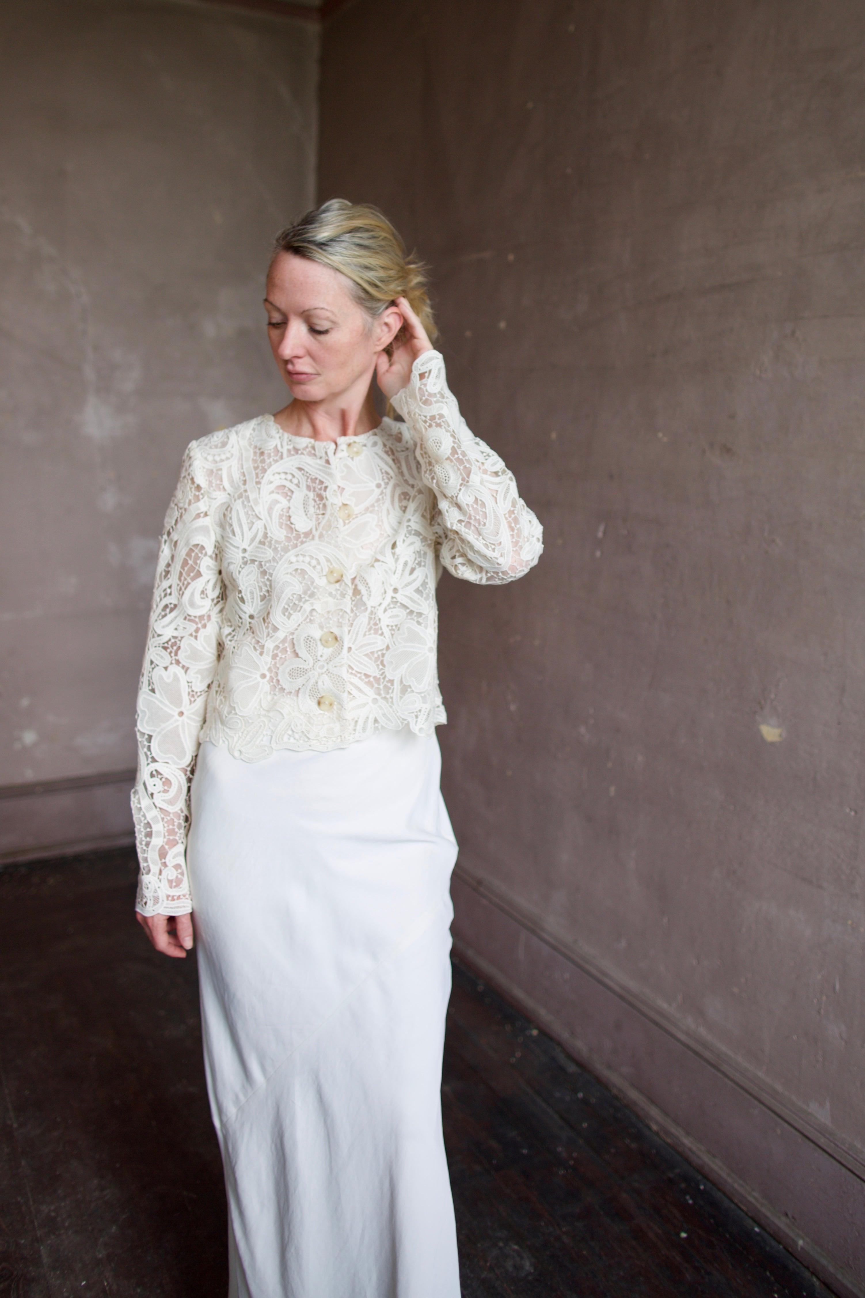 Mature model wearing designer jacket by Ulla Johnson. This delicate white lace button down jacket features an embroidered floral design