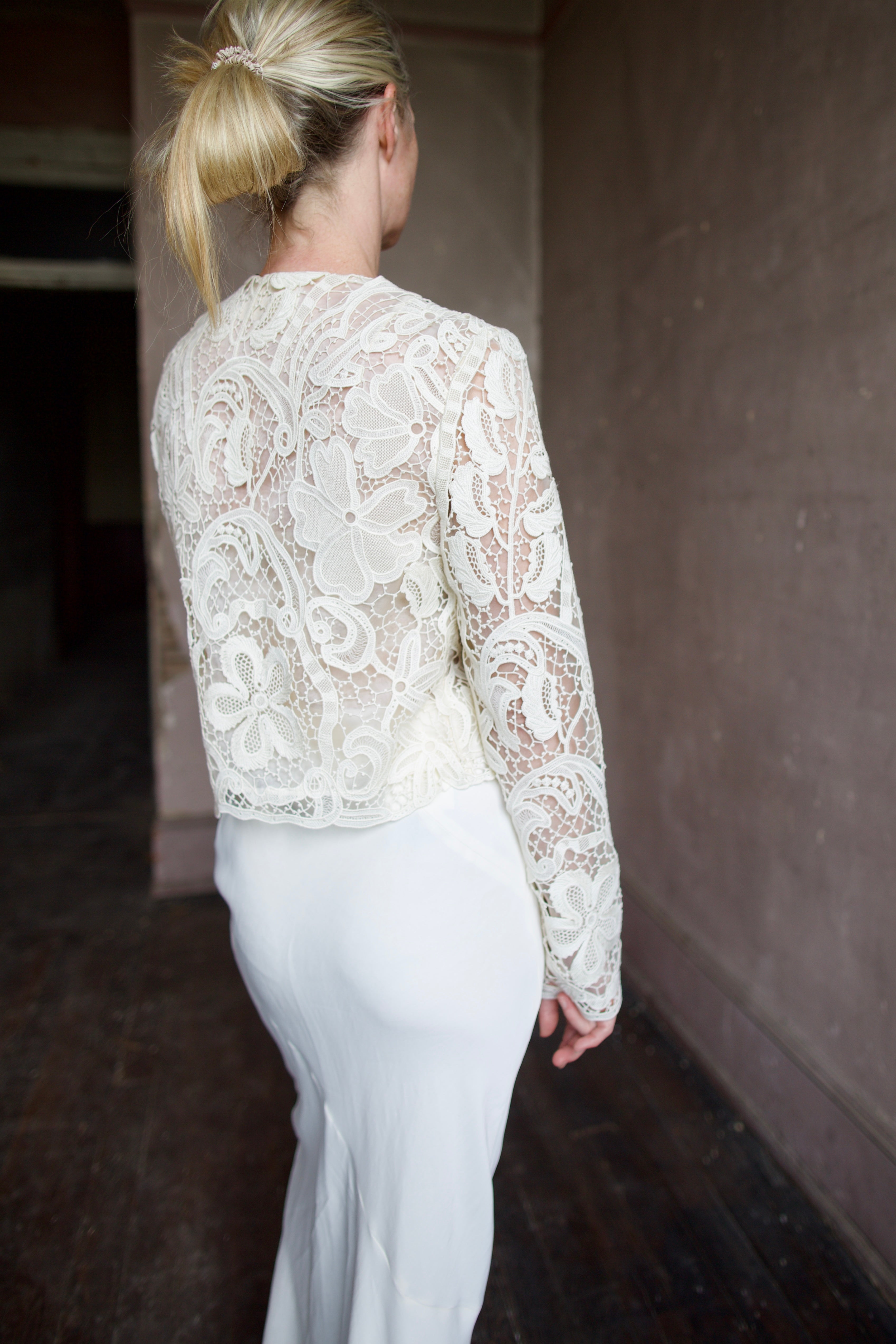 Mature model wearing designer jacket by Ulla Johnson. This delicate white lace button down jacket features an embroidered floral design