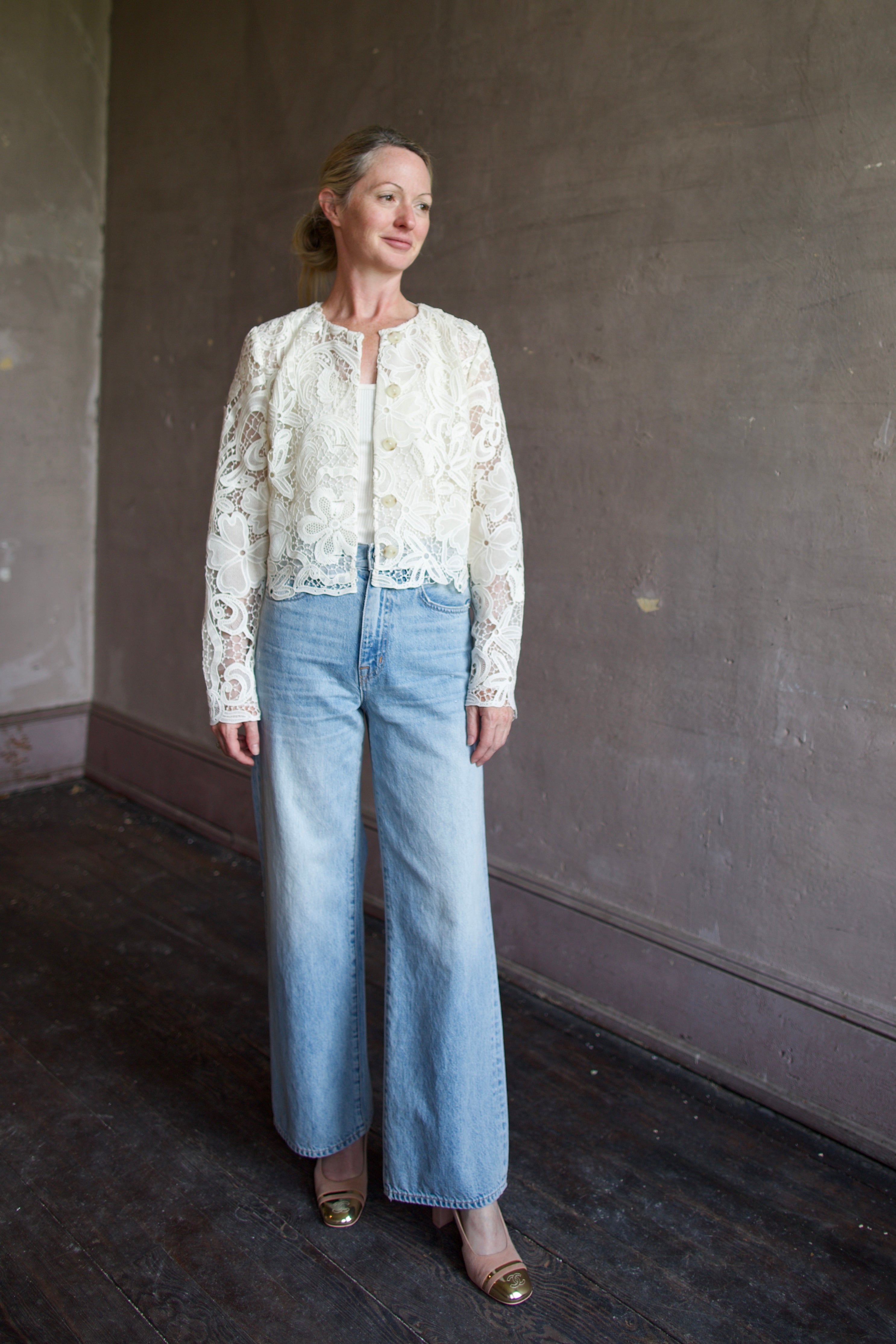 Mature model wearing timeless lace jacket by Ulla Johnson. This elegant button down jacket features an intricate floral design in white lace