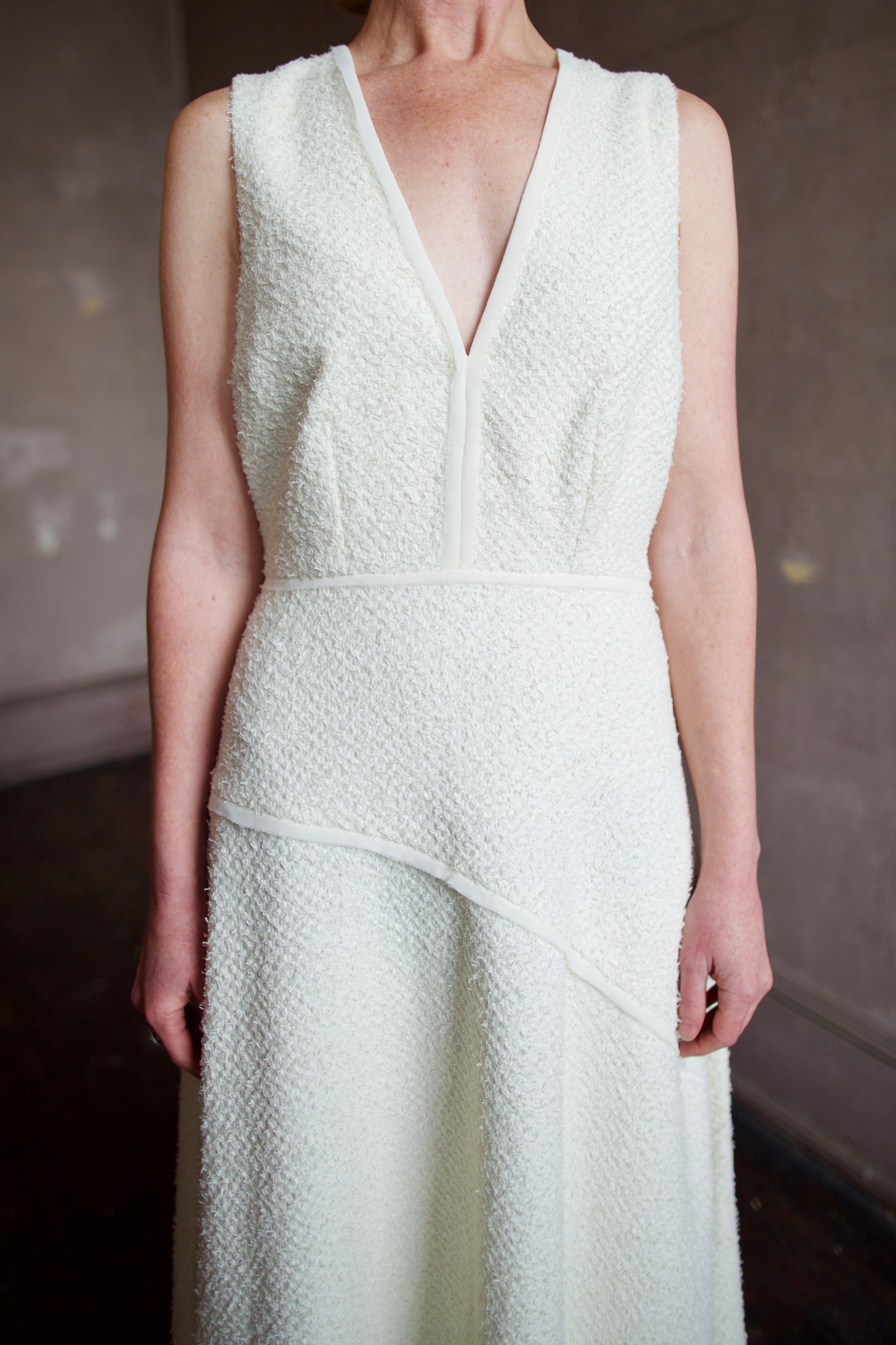 Woman wearing luxury designer Ulla Johnson Florence Dress in textured off-white cotton blend with a v-neckline and asymmetrical hemline