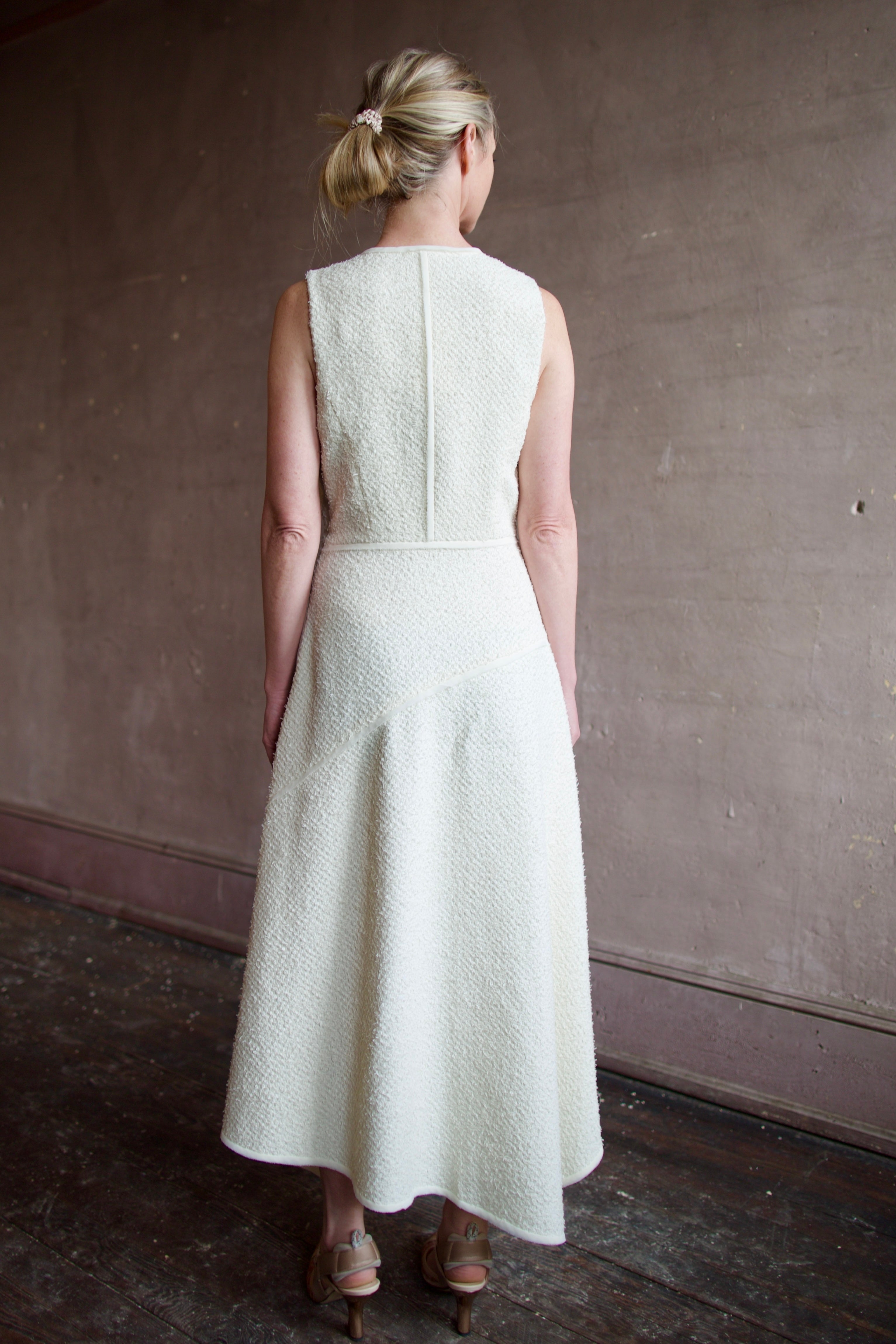 Woman wearing luxury designer Ulla Johnson Florence Dress in textured off-white cotton blend with a v-neckline and asymmetrical hemline