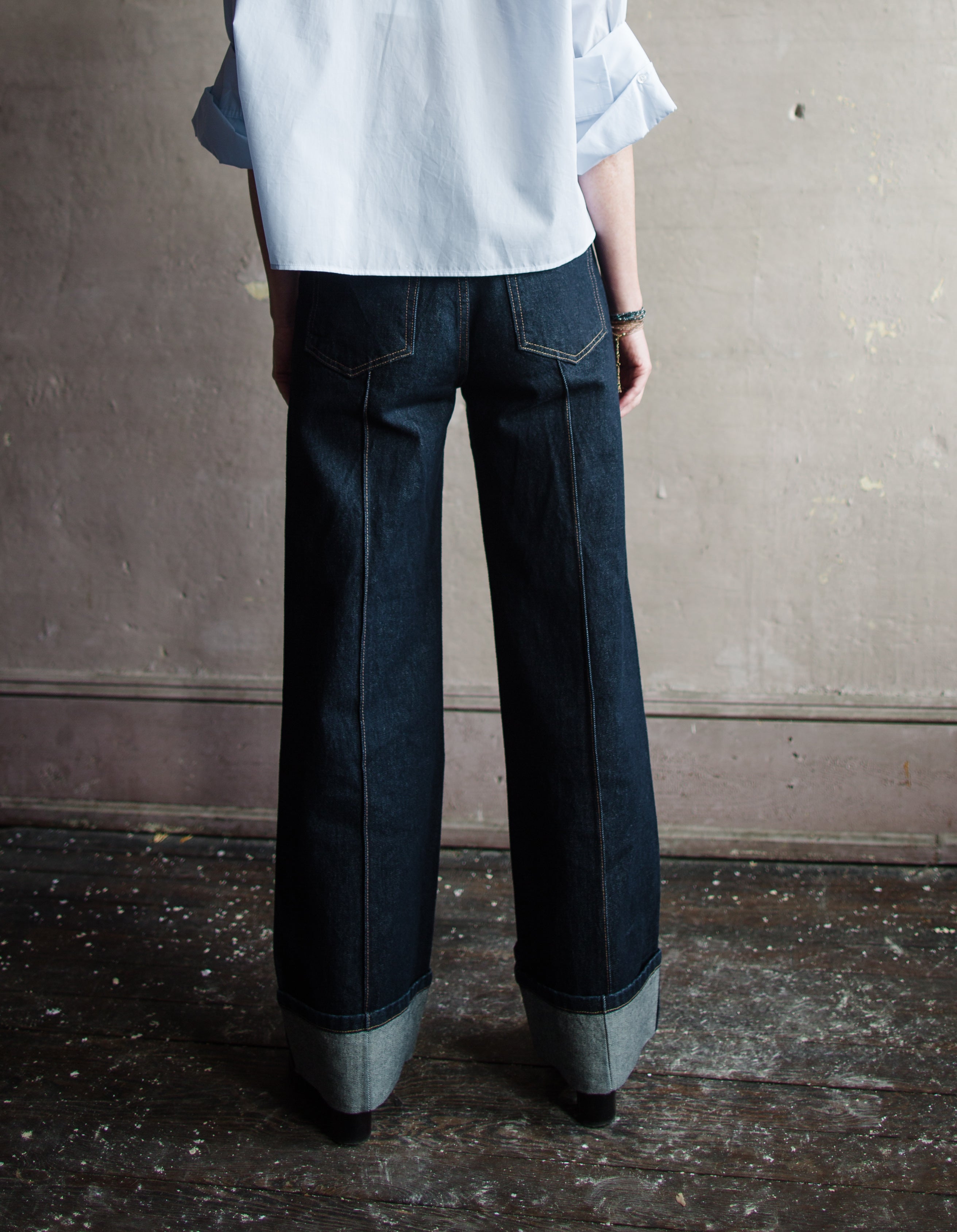 Image featuring a woman wearing Ulla Johnson Genevieve Jean with pintucking detail down middle front and back legs in a dark denim finish with no distressing.