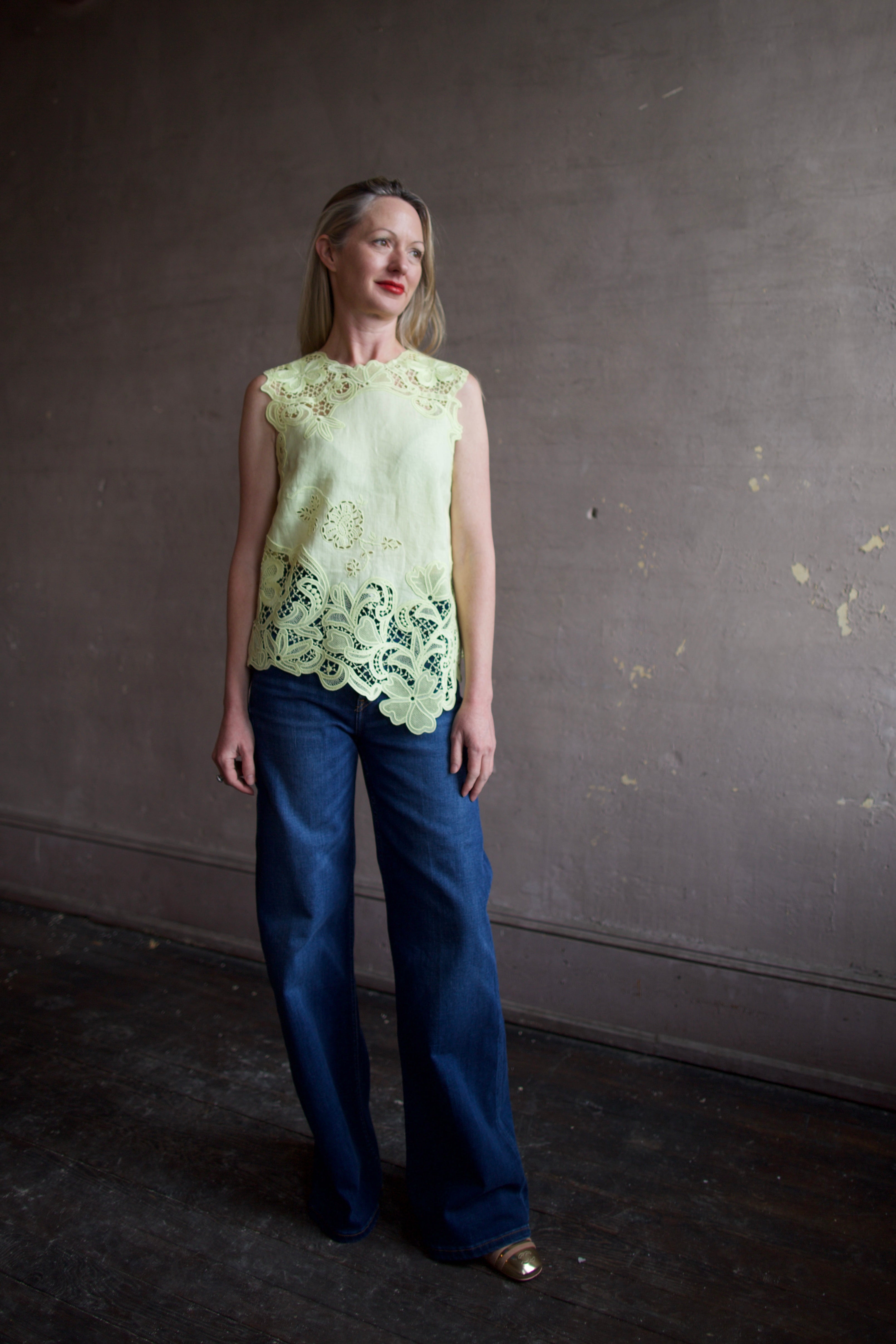 Mature woman wearing luxury designer Ulla Johnson Marlis premium linen sleeveless top in citrine distinctive asymmetric hemline