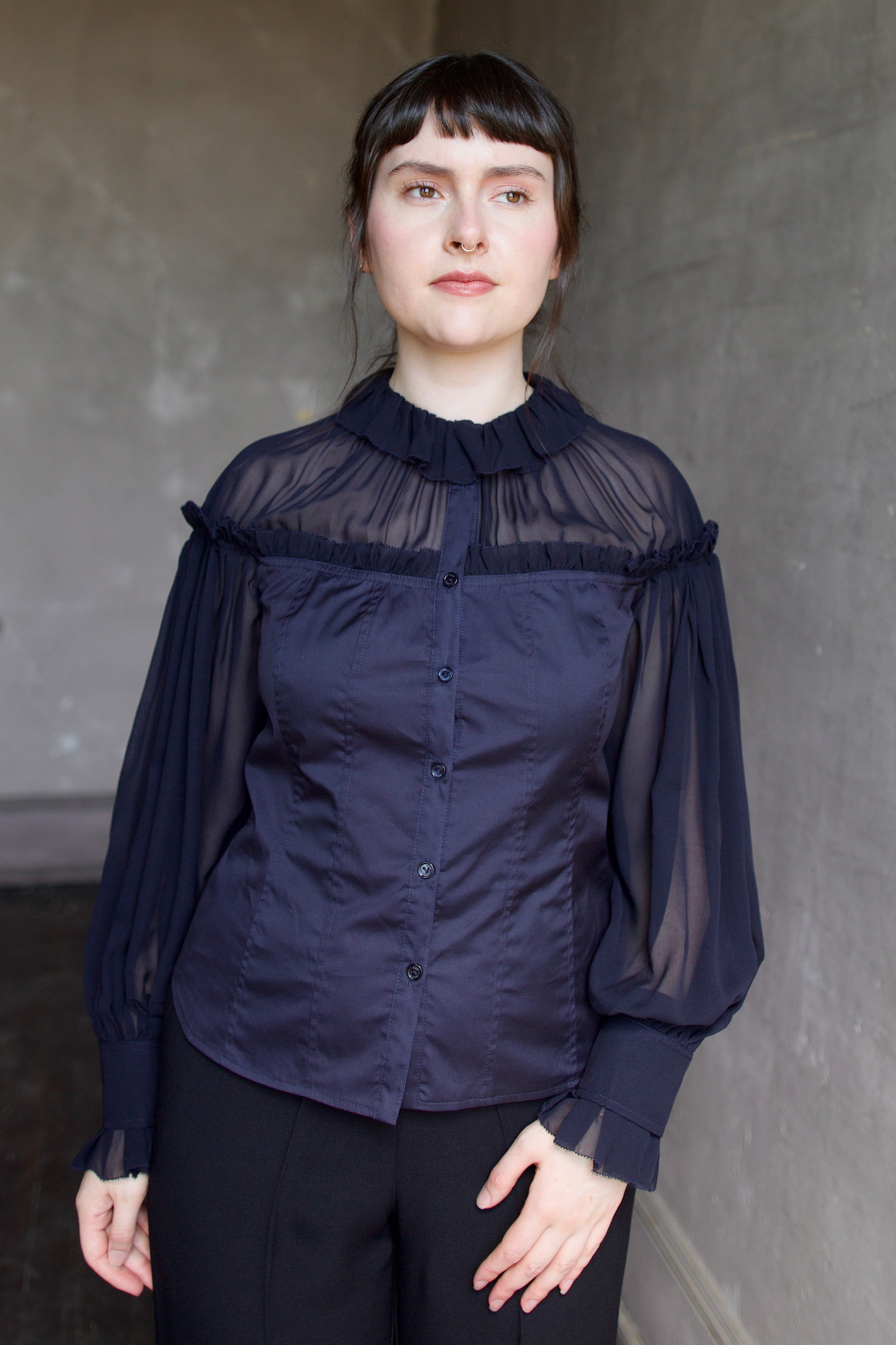 Woman wearing a dark blue cotton and silk blouse with sheer long sleeves by designer Ulla Johnson