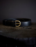 Image of the black belt by Ulla Johnson featuring a twisted gold buckle and smooth leather body.