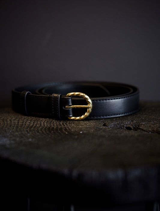 Image of the black belt by Ulla Johnson featuring a twisted gold buckle and smooth leather body.