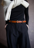 close up image of a woman wearing the Ulla Johnson gia belt, Apiece Apart merino sweater and mirabelle trousers and Naadam ultraluxe sweater