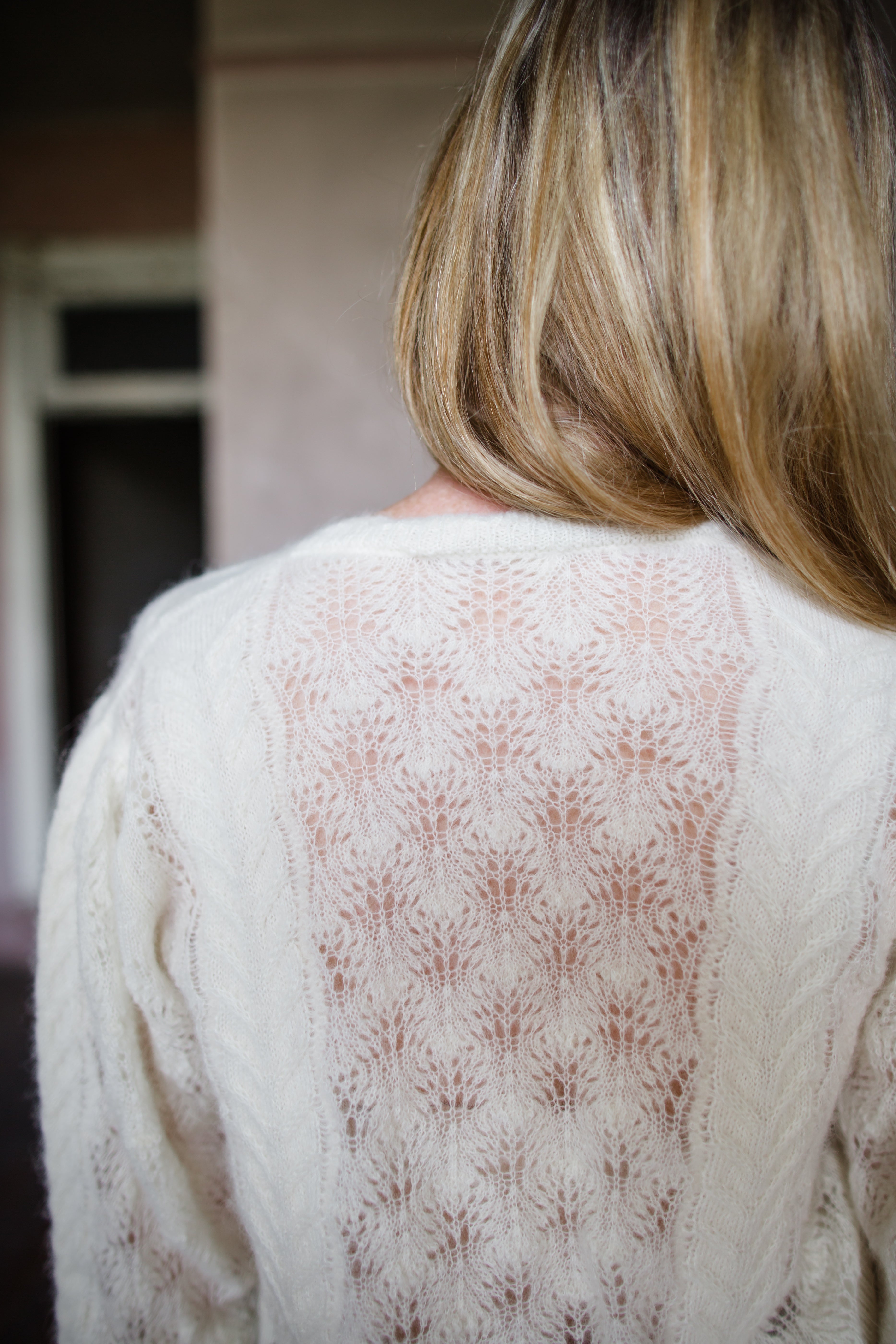 Image featuring a woman wearing the Haley sweater by Ulla Johnson with a slightly sheer weave, mother of pearl buttons and long sleeves in ivory alpaca.