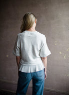 Mature woman wearing the Ulla Johnson Harper Top grey short sleeve sweatshirt with layered white top 