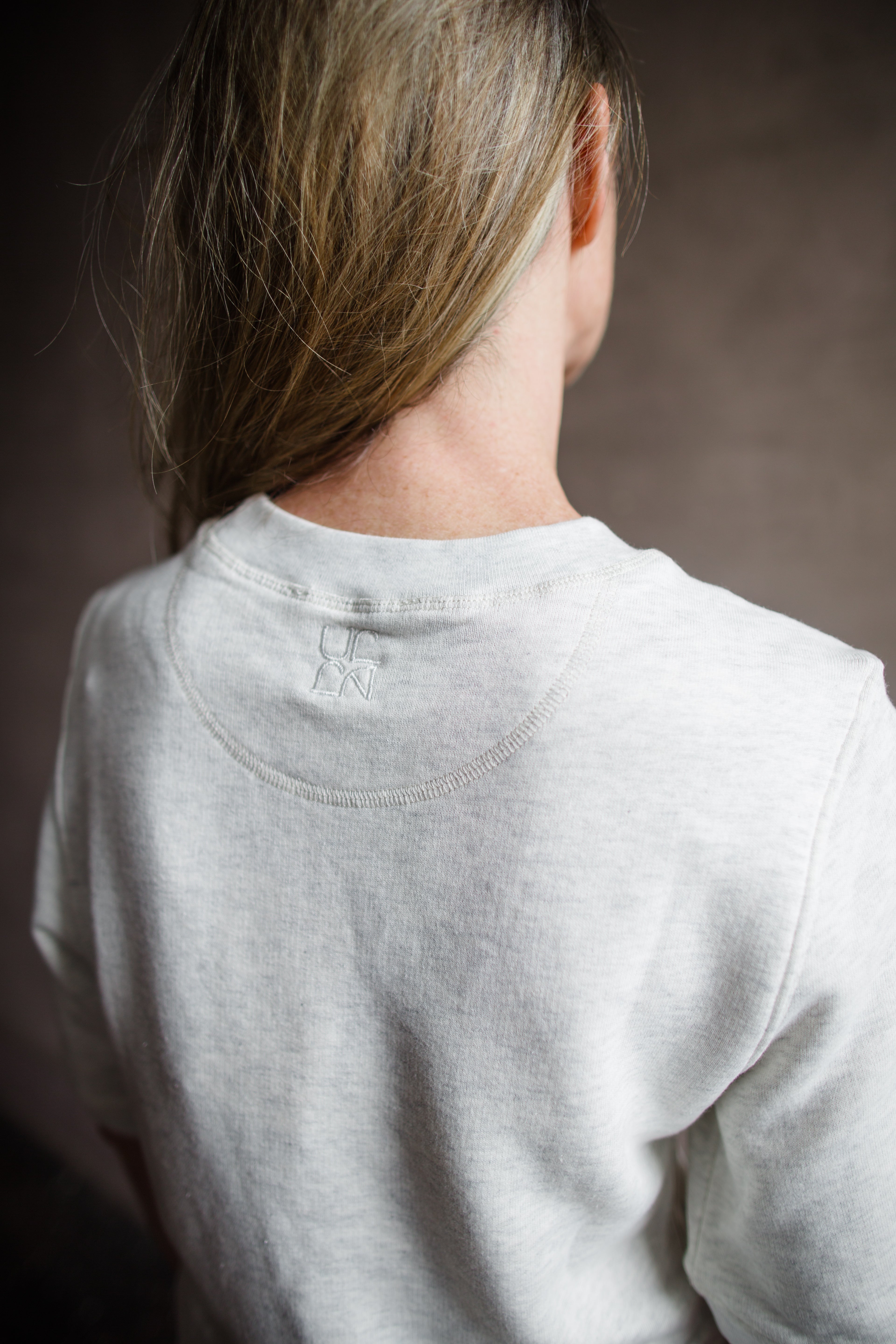 Mature woman wearing the Ulla Johnson Harper  Top grey short sleeve sweatshirt with layered white top 