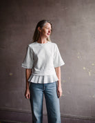 Mature woman wearing the Ulla Johnson Harper  Top grey short sleeve sweatshirt with layered white top 