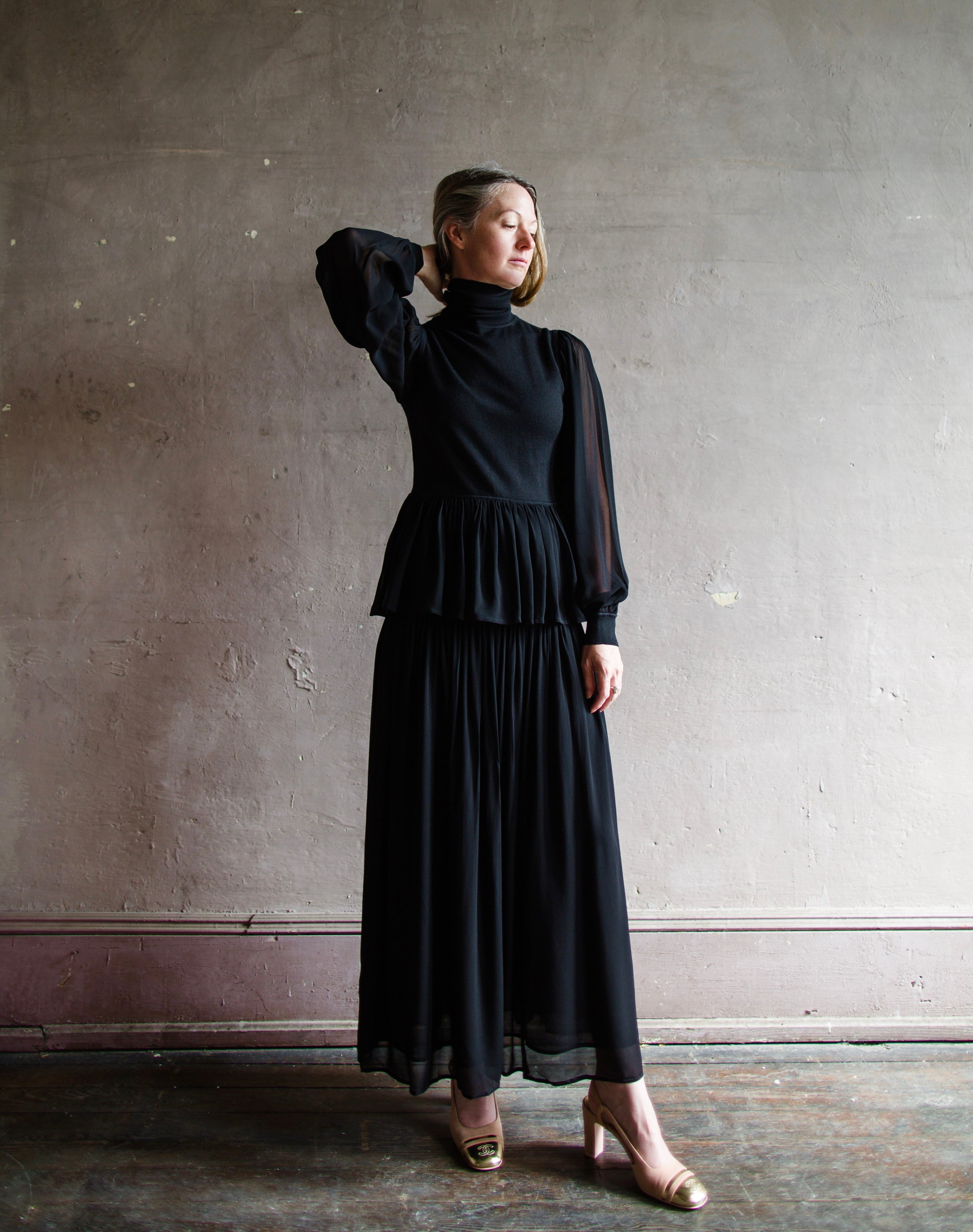 Image featuring a woman wearing the Miya black skirt by Ulla Johnson features a tailored fit though the hips with pleated skirting and a midi hem.