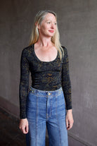 Mature model wearing a black multi-color long-sleeve fitted jersey top by premium designer Ulla Johnson