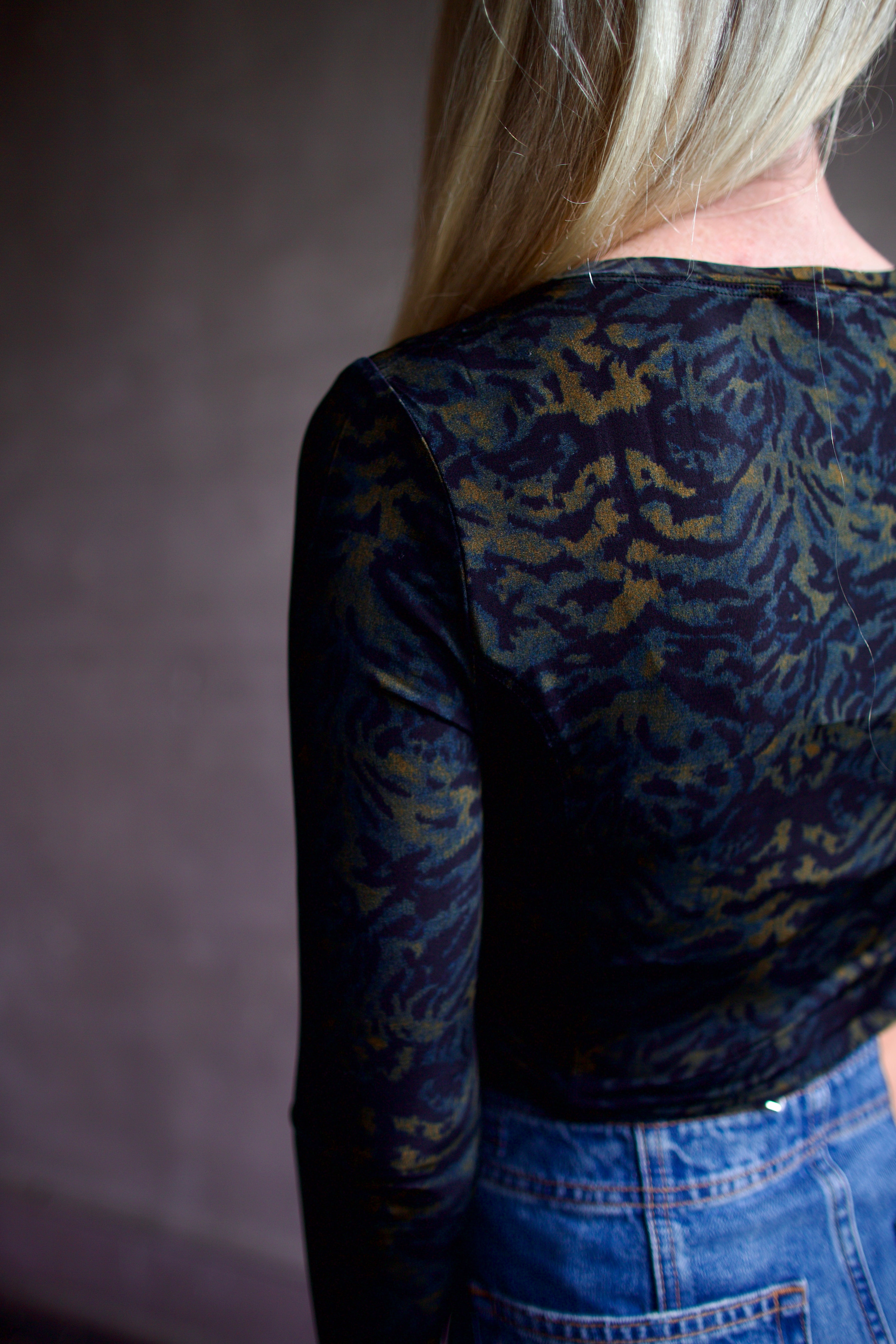 Mature model wearing a black multi-color long-sleeve fitted jersey top by premium designer Ulla Johnson