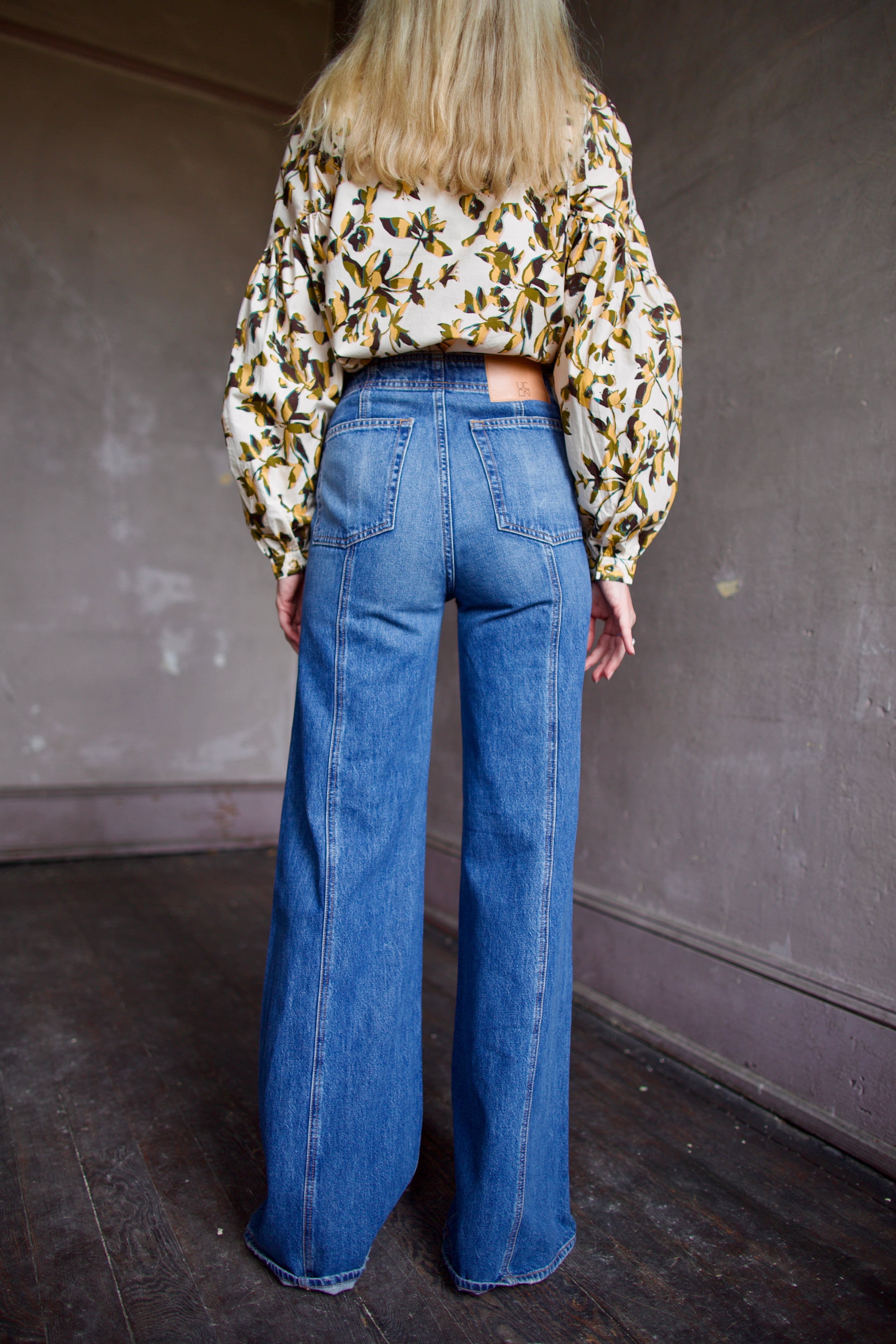 Model wearing a floral blouse and expertly designed blue flared denim by New York designer Ulla Johnson