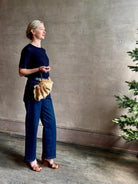 Mature woman with designer Ulla Johnson Adria crossbody bag with raffia-textured exterior and removeable handle that can double as a clutch in a natural raffia tone