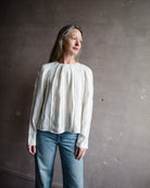 Mature woman wearing Ulla Johnson Kavi long sleeve Blouse with three dimensional linear details crew neck hidden closure