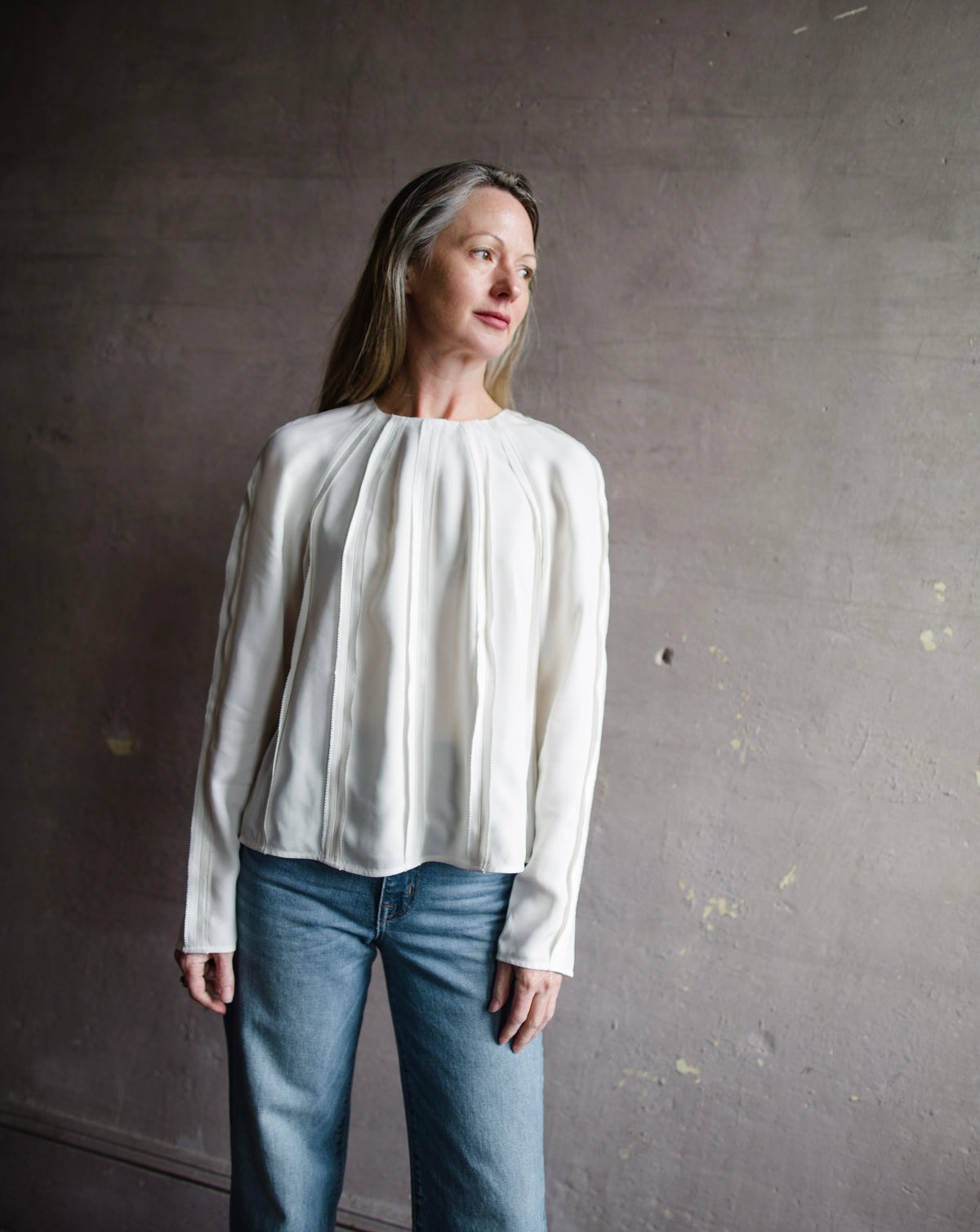 Mature woman wearing Ulla Johnson Kavi long sleeve Blouse with three dimensional linear details crew neck hidden closure