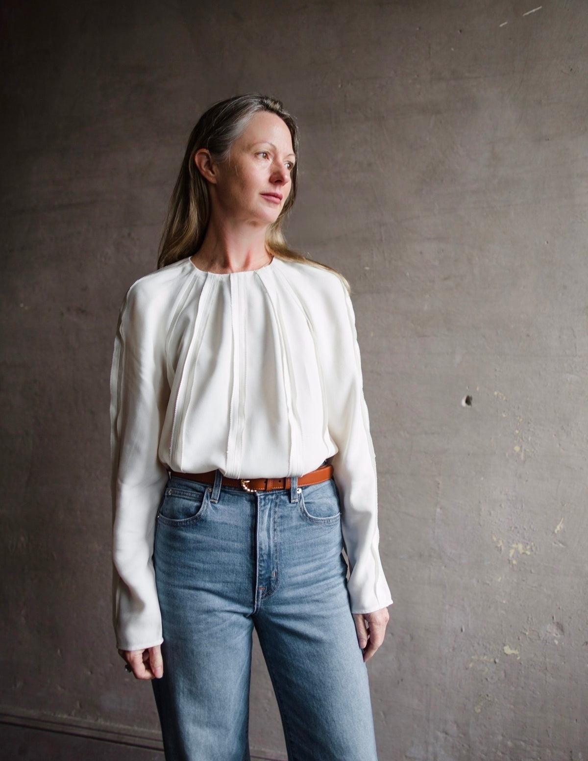 Mature woman wearing designer Ulla Johnson Kavi long sleeve Blouse  tucked in with three dimensional linear details crew neck and hidden closure