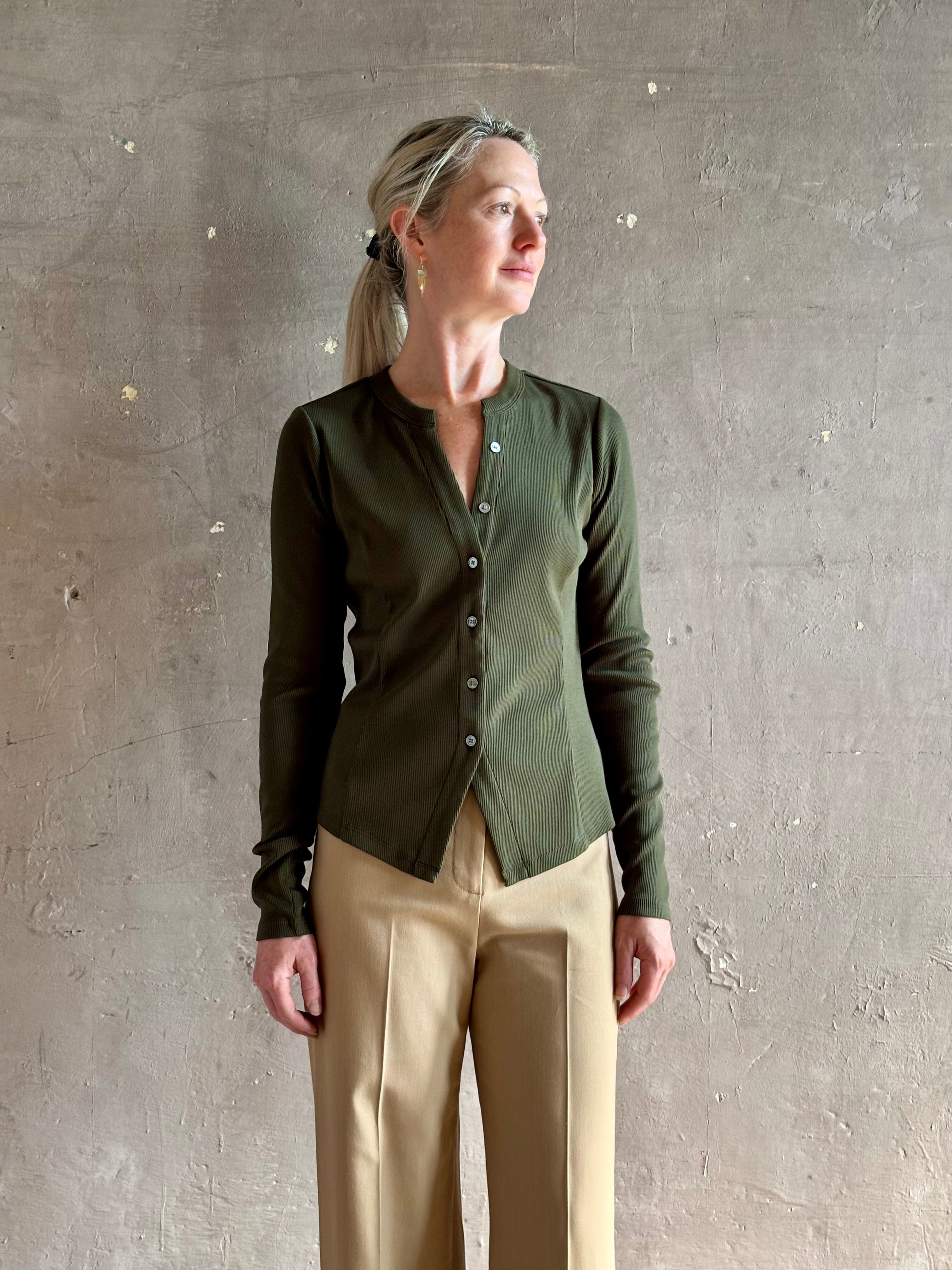 Mature womanwearing a dark green long-sleeve ribbed cotton henley top designer Veronica Beard Cordis v-neck