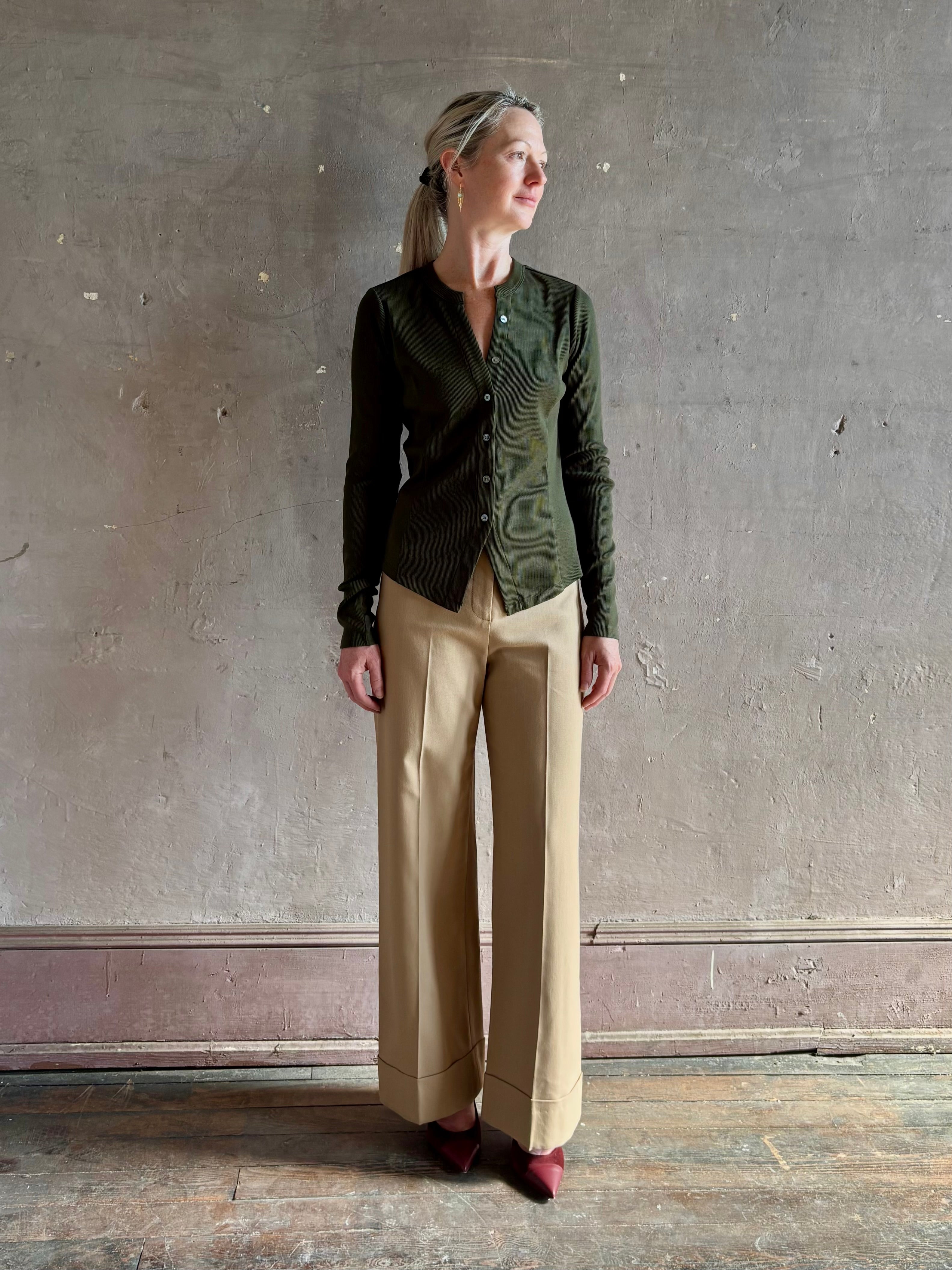 Mature womanwearing a dark green long-sleeve ribbed cotton henley top designer Veronica Beard Cordis v-neck