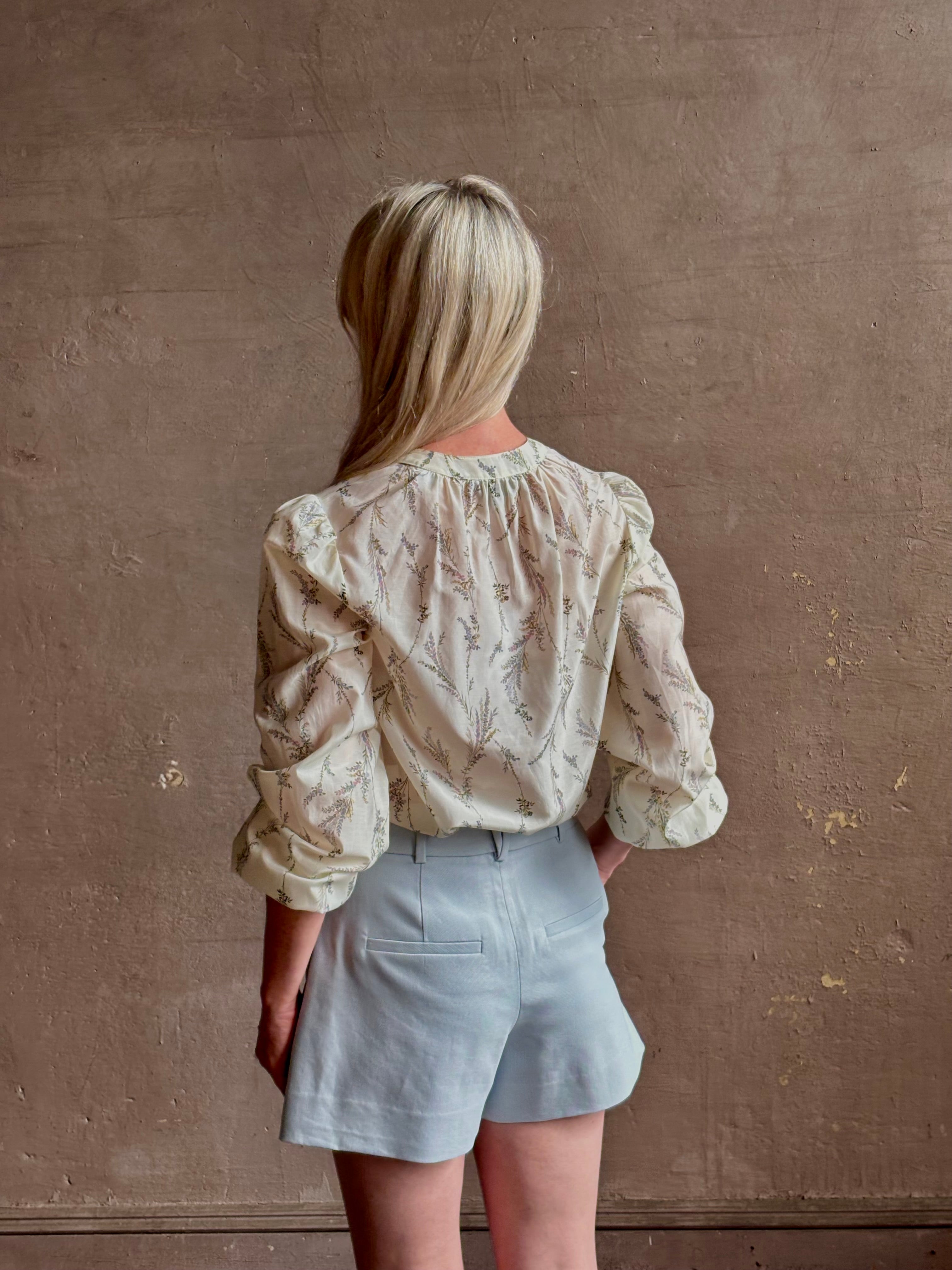 Mature woman wearing elevated Craig Short from Veronica Beard a sophisticated women's designer short rendered in river mist light blue and crafted from a refined blend of cotton and viscose with side pockets, one front pleat and tailored waistband with belt loops