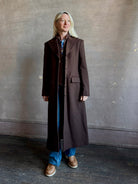 Mature woman wearing Veronica Beard Elspeth Coat with OVS Hoodie Dickey in Espresso brown wool-cashmere A-line coat with a removable hoodie layer. Playful, sculptural cold-weather luxury.