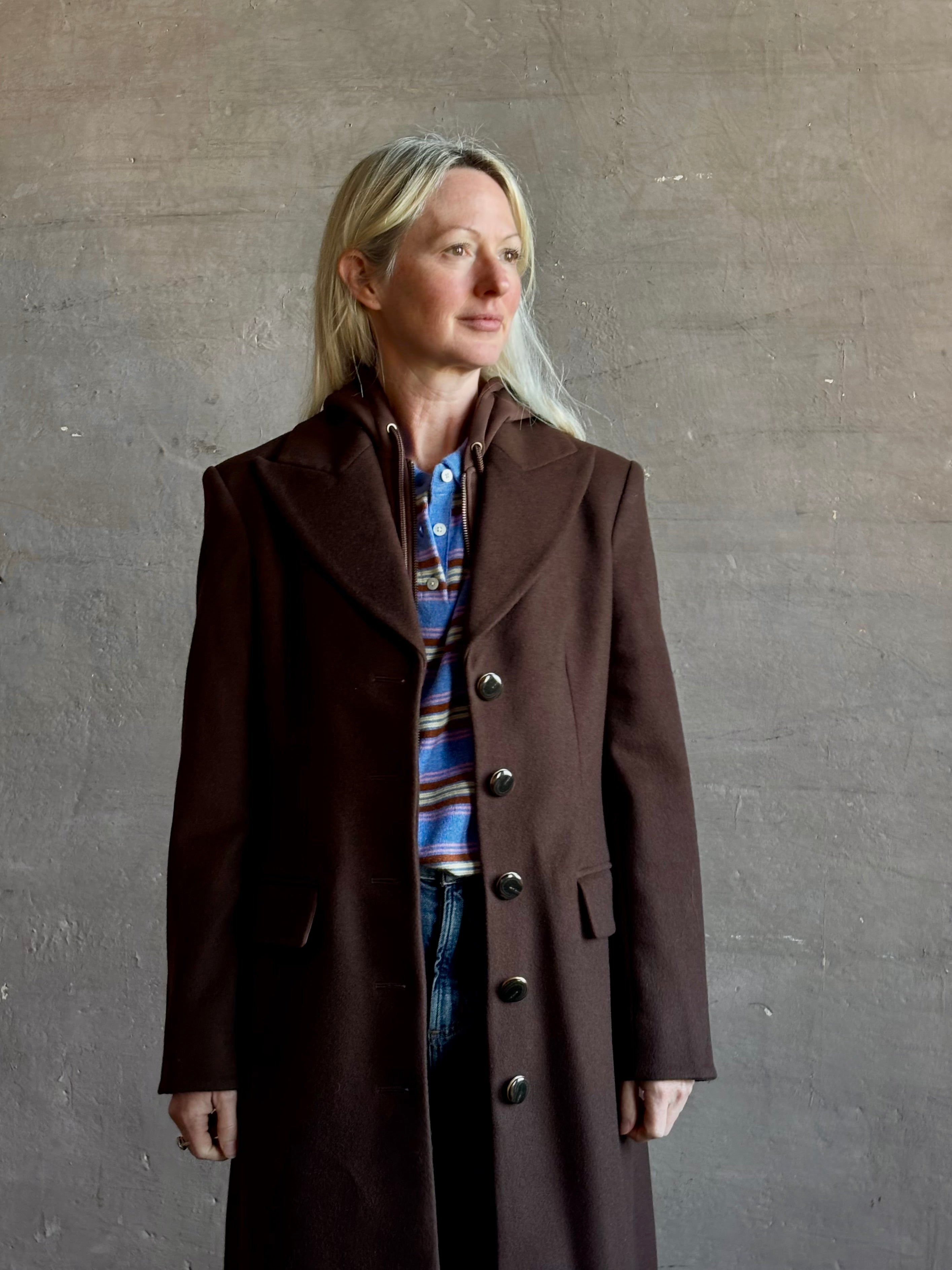 Mature woman wearing Veronica Beard Elspeth Coat with OVS Hoodie Dickey in Espresso brown wool-cashmere A-line coat with a removable hoodie layer. Playful, sculptural cold-weather luxury.