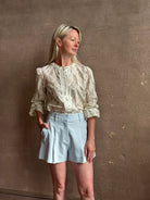 Mature woman wearing luxurious tailored Emiko Blouse from Veronica Beard a women's designer blouse rendered in a cream  ground adorned with a delicate prairie floral print and crafted from a cotton and silk blend with long sleeves, button front and round mandarin collar.