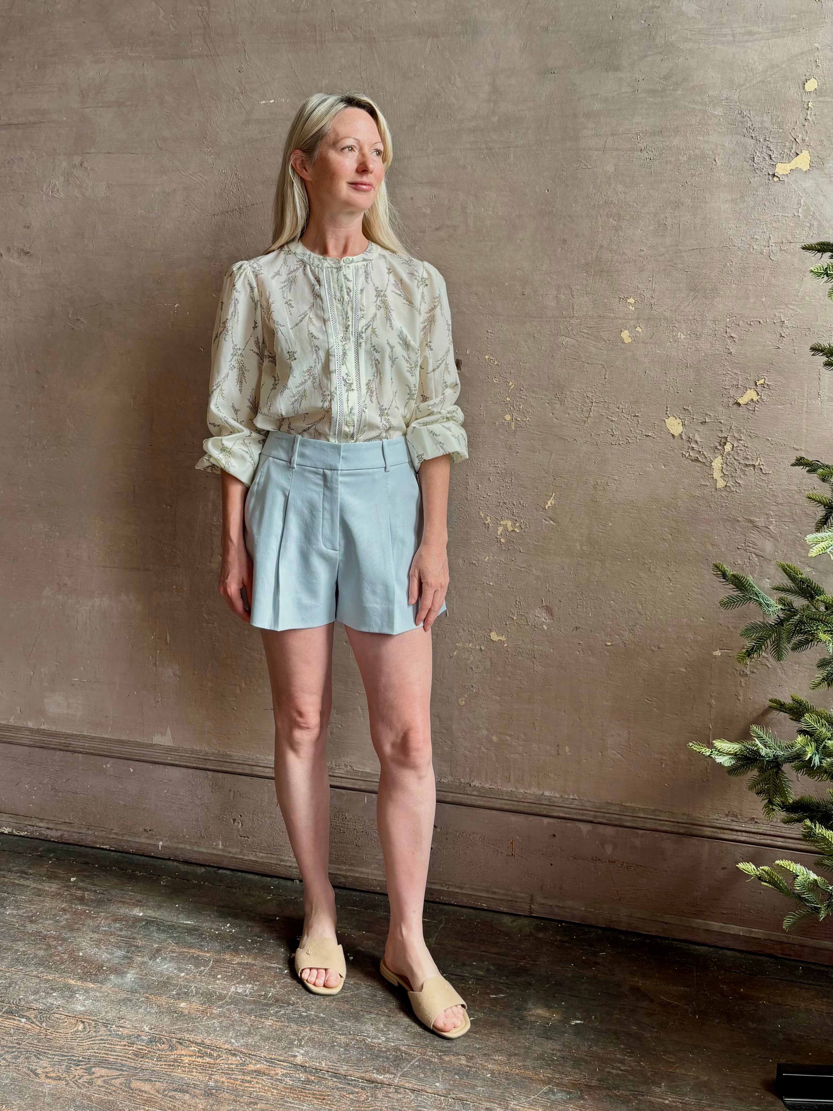 Mature woman wearing luxurious tailored Emiko Blouse from Veronica Beard a women's designer blouse rendered in a cream  ground adorned with a delicate prairie floral print and crafted from a cotton and silk blend with long sleeves, button front and round mandarin collar.