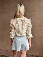 Mature woman wearing luxurious tailored Emiko Blouse from Veronica Beard a women's designer blouse rendered in a cream  ground adorned with a delicate prairie floral print and crafted from a cotton and silk blend with long sleeves, button front and round mandarin collar.