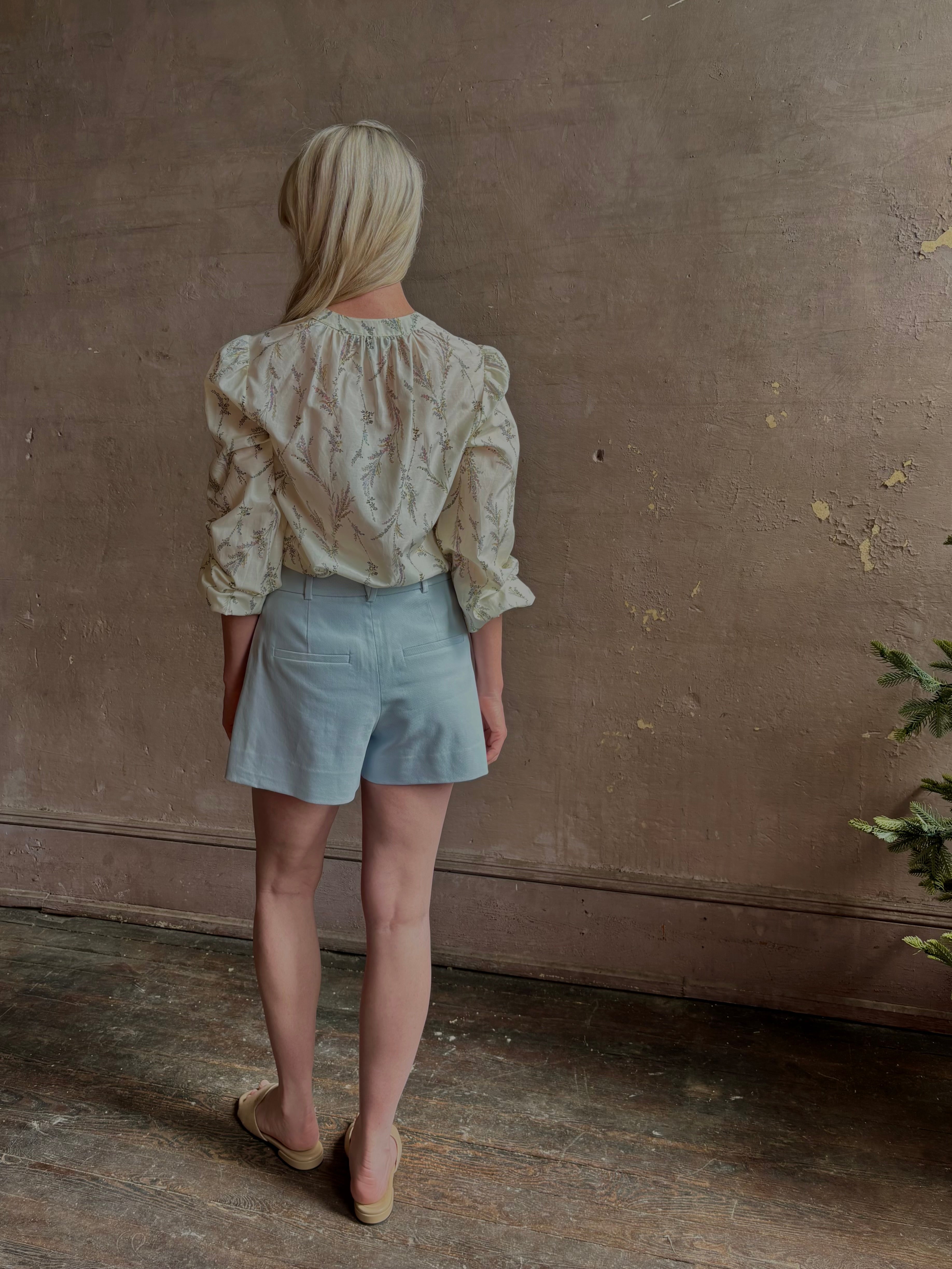 Mature woman wearing luxurious tailored Emiko Blouse from Veronica Beard a women's designer blouse rendered in a cream  ground adorned with a delicate prairie floral print and crafted from a cotton and silk blend with long sleeves, button front and round mandarin collar.