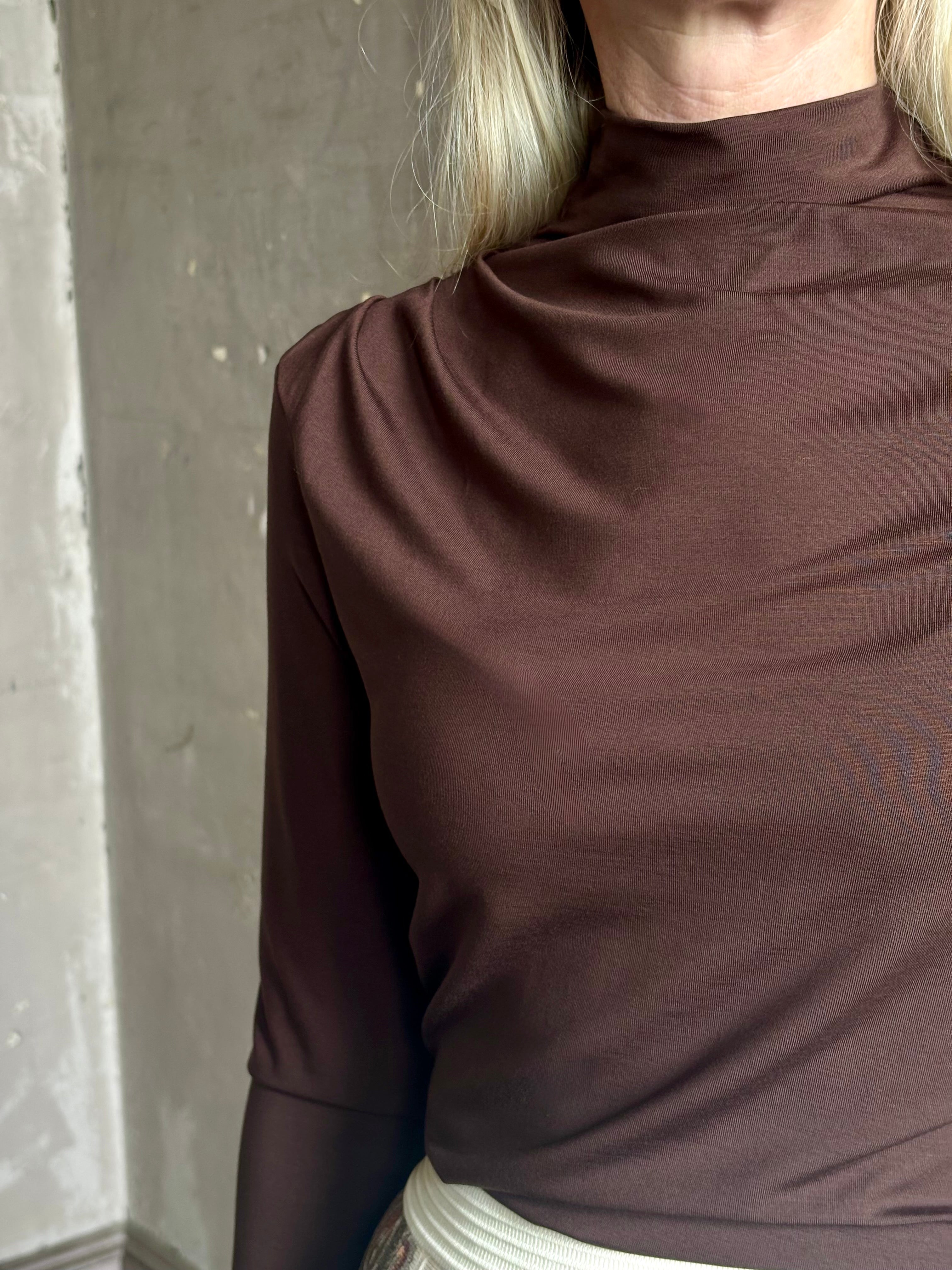 Mature woman wearing Veronica Beard's Mylie Top in Espresso brown lightweight lyocell with asymmetrical shoulder draping and side ruching