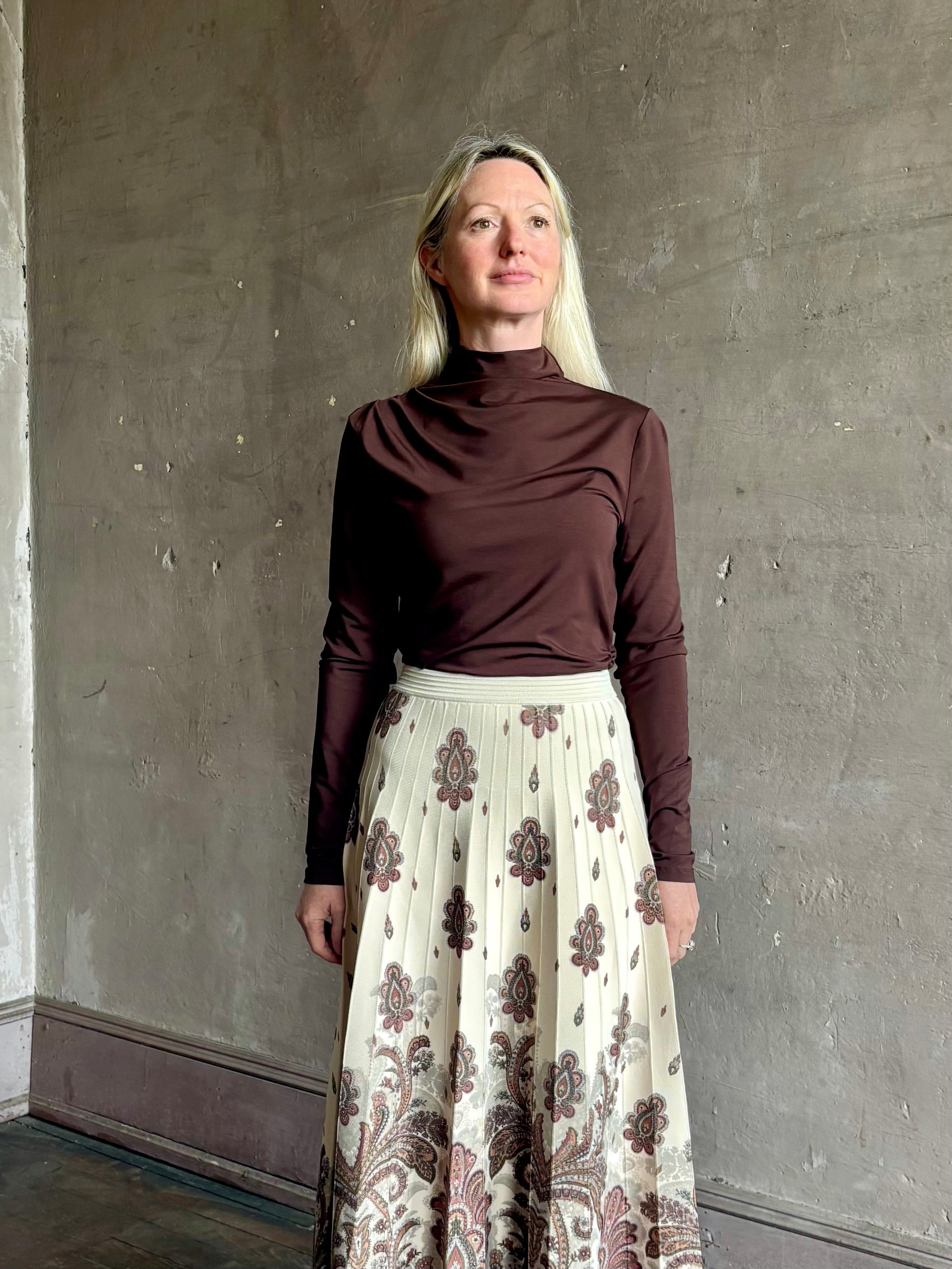Mature woman wearing Veronica Beard's Mylie Top in Espresso brown lightweight lyocell with asymmetrical shoulder draping and side ruching