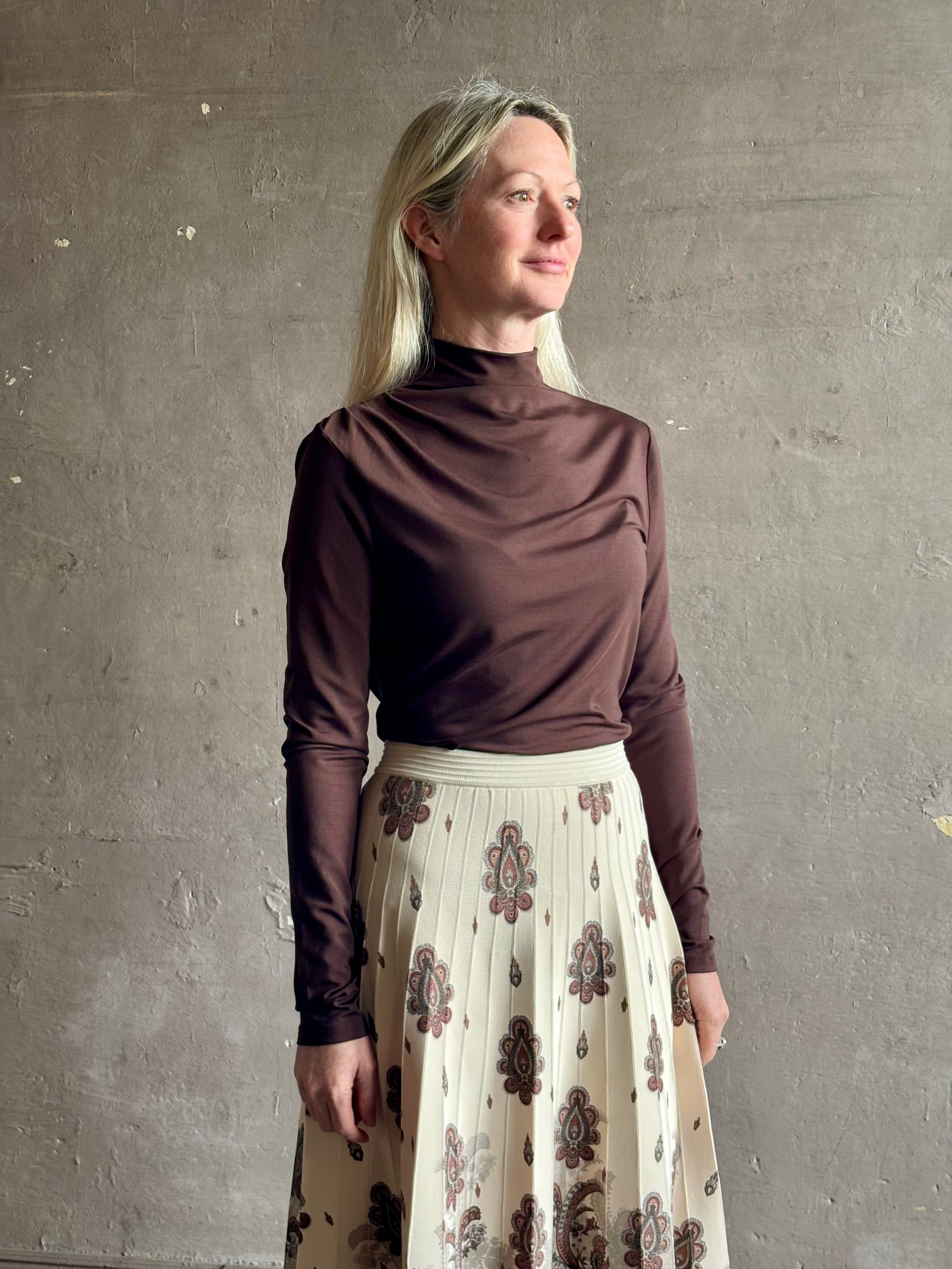 Mature woman wearing Veronica Beard's Mylie Top in Espresso brown lightweight lyocell with asymmetrical shoulder draping and side ruching