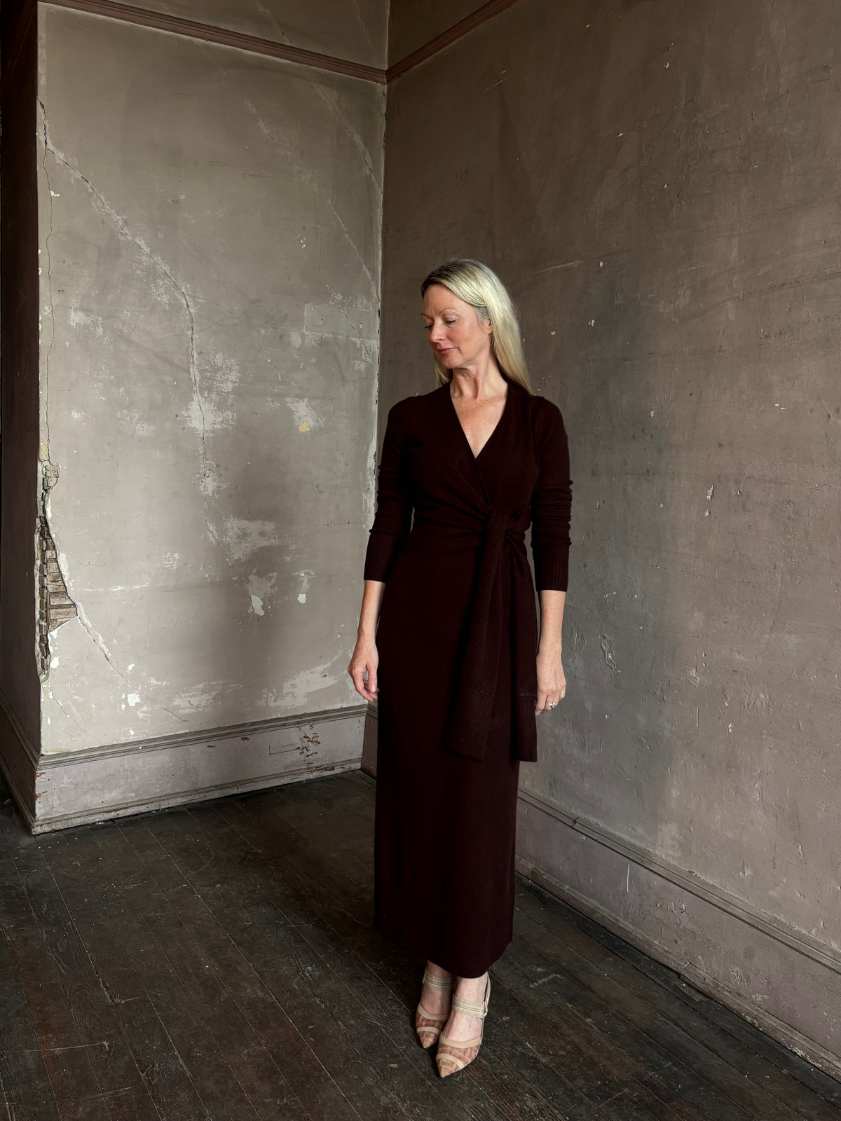 Mature woman wearing Veronica Beard's Salomez Knit Dress in chocolate brown  wrap maxi with a V-neckline and side vent