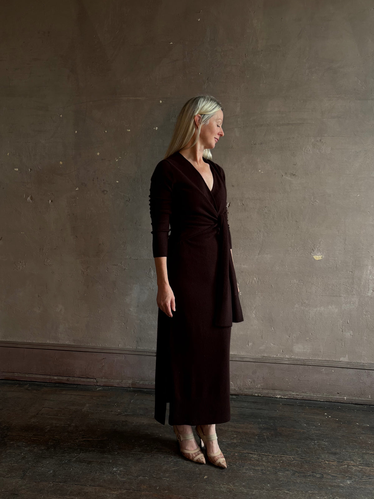 Mature woman wearing Veronica Beard's Salomez Knit Dress in chocolate brown  wrap maxi with a V-neckline and side vent