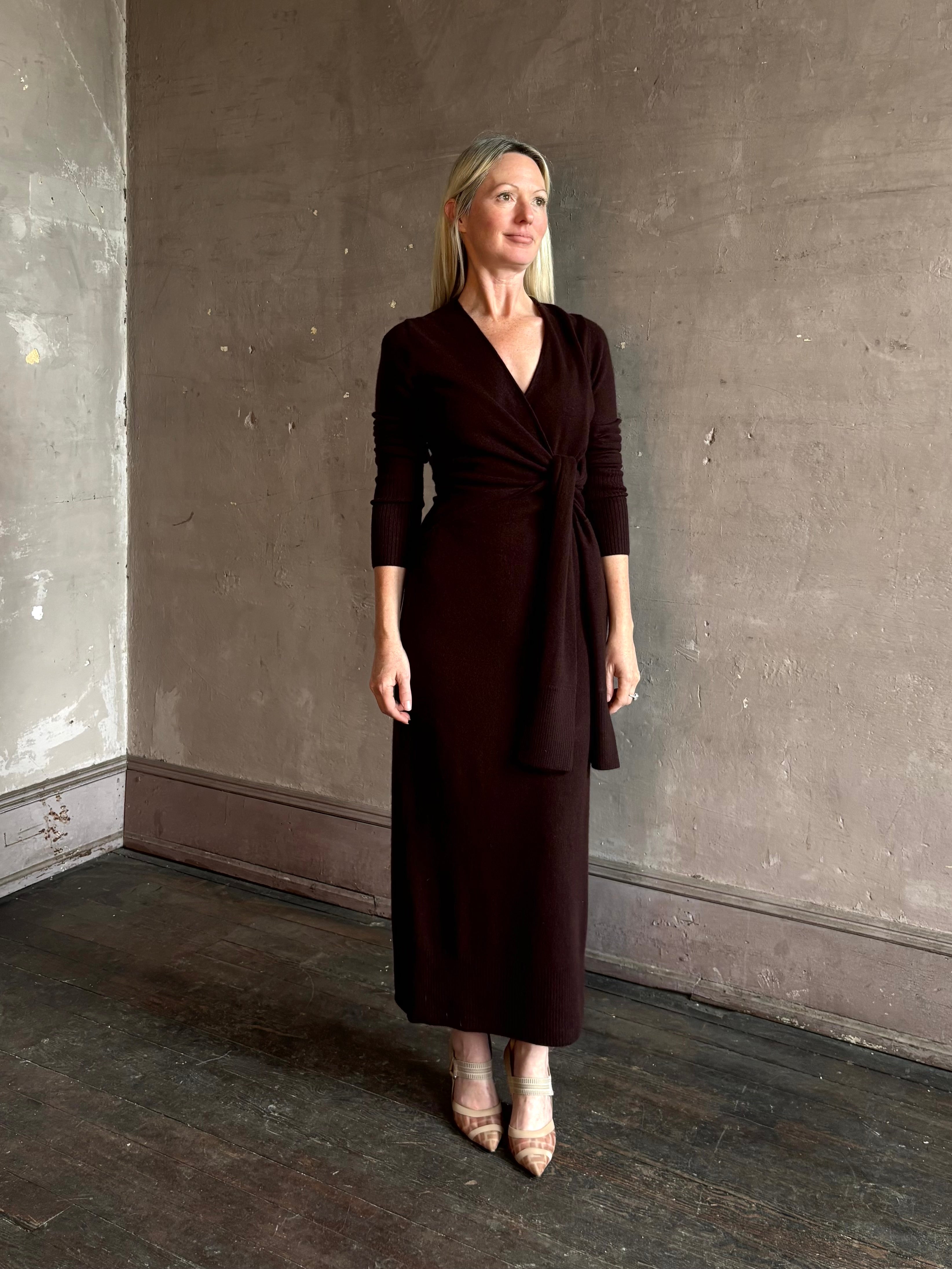 Mature woman wearing Veronica Beard's Salomez Knit Dress in chocolate brown  wrap maxi with a V-neckline and side vent