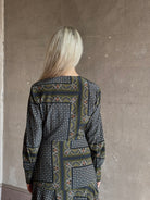 Mature woman wearing long-sleeved maxi dress in a geometric and floral block-print pattern in green navy and white