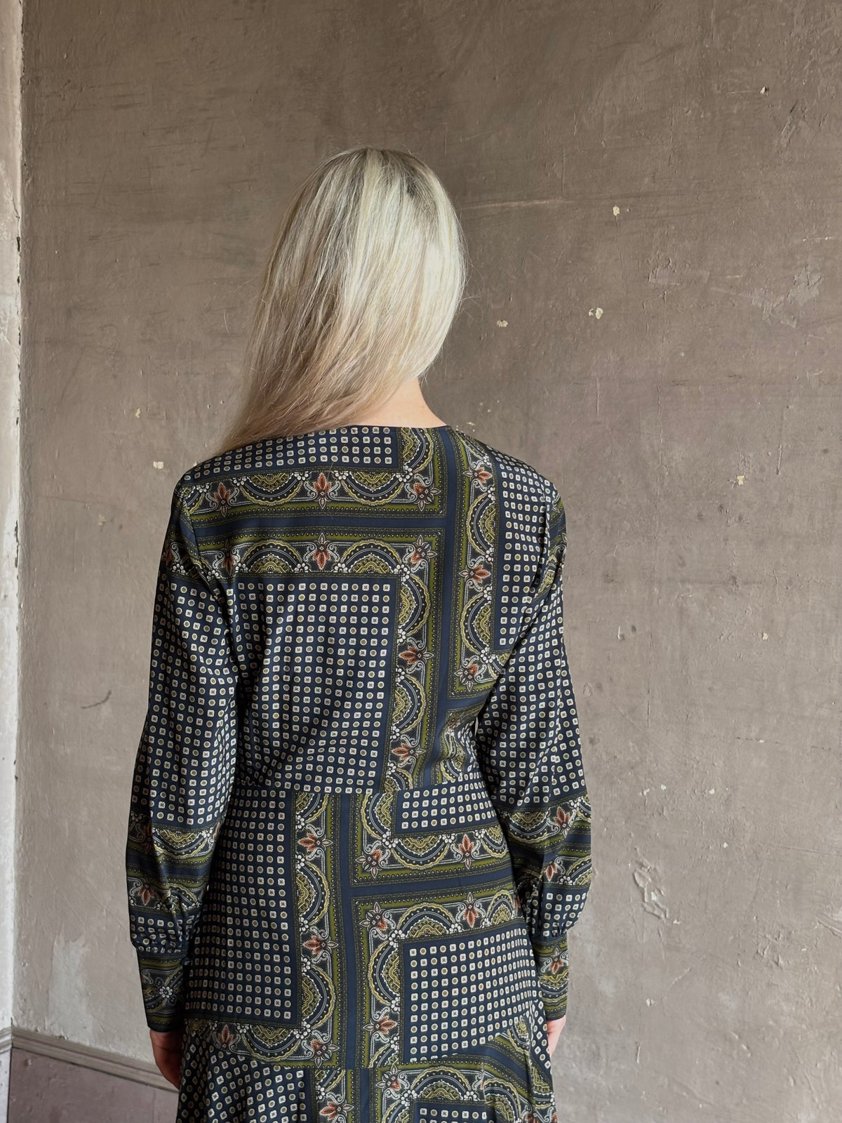 Mature woman wearing long-sleeved maxi dress in a geometric and floral block-print pattern in green navy and white