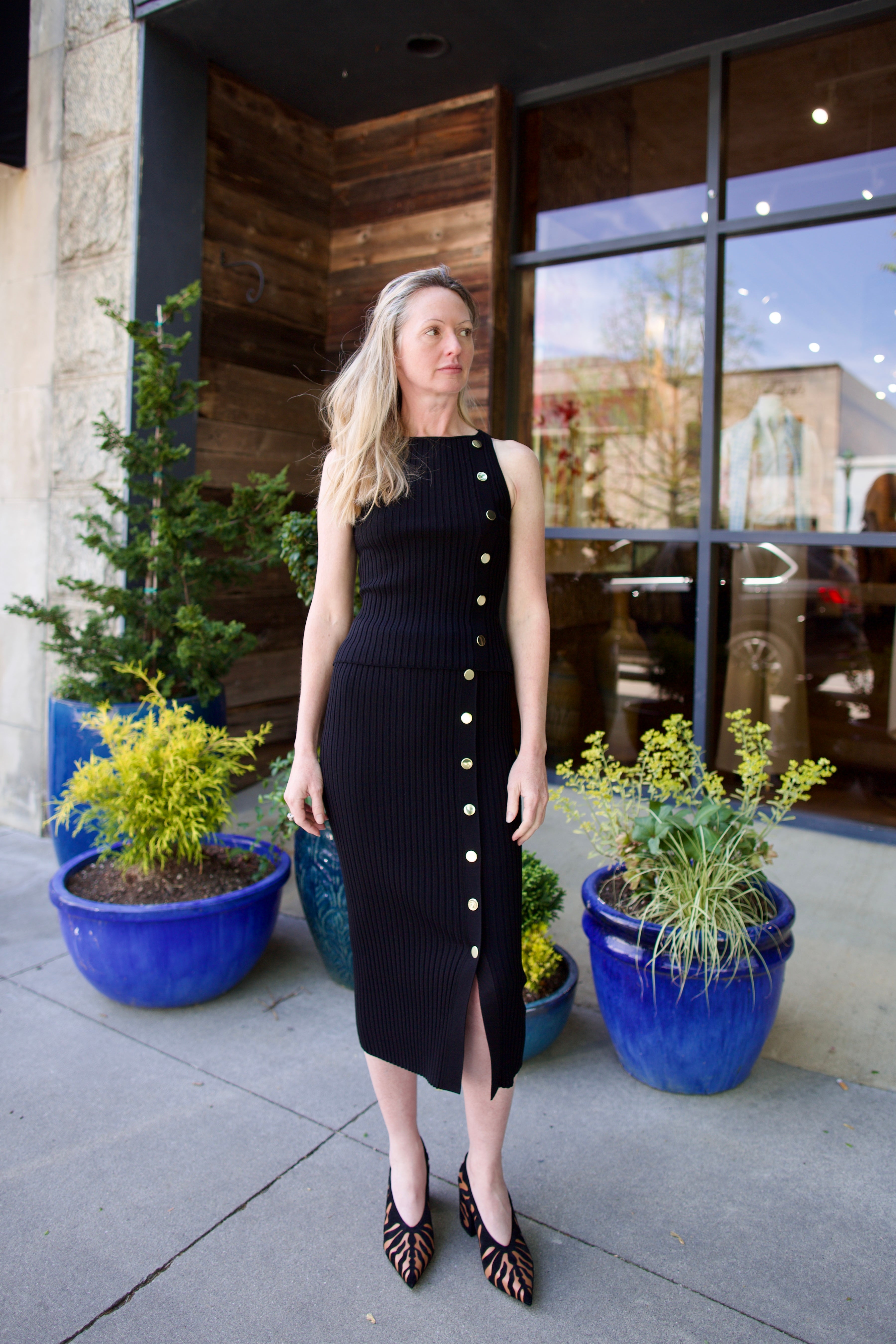 woman wearing Veronica Beard black knit Tanner Skirt with gold buttons leg vent comfy stretchy ribbed texture