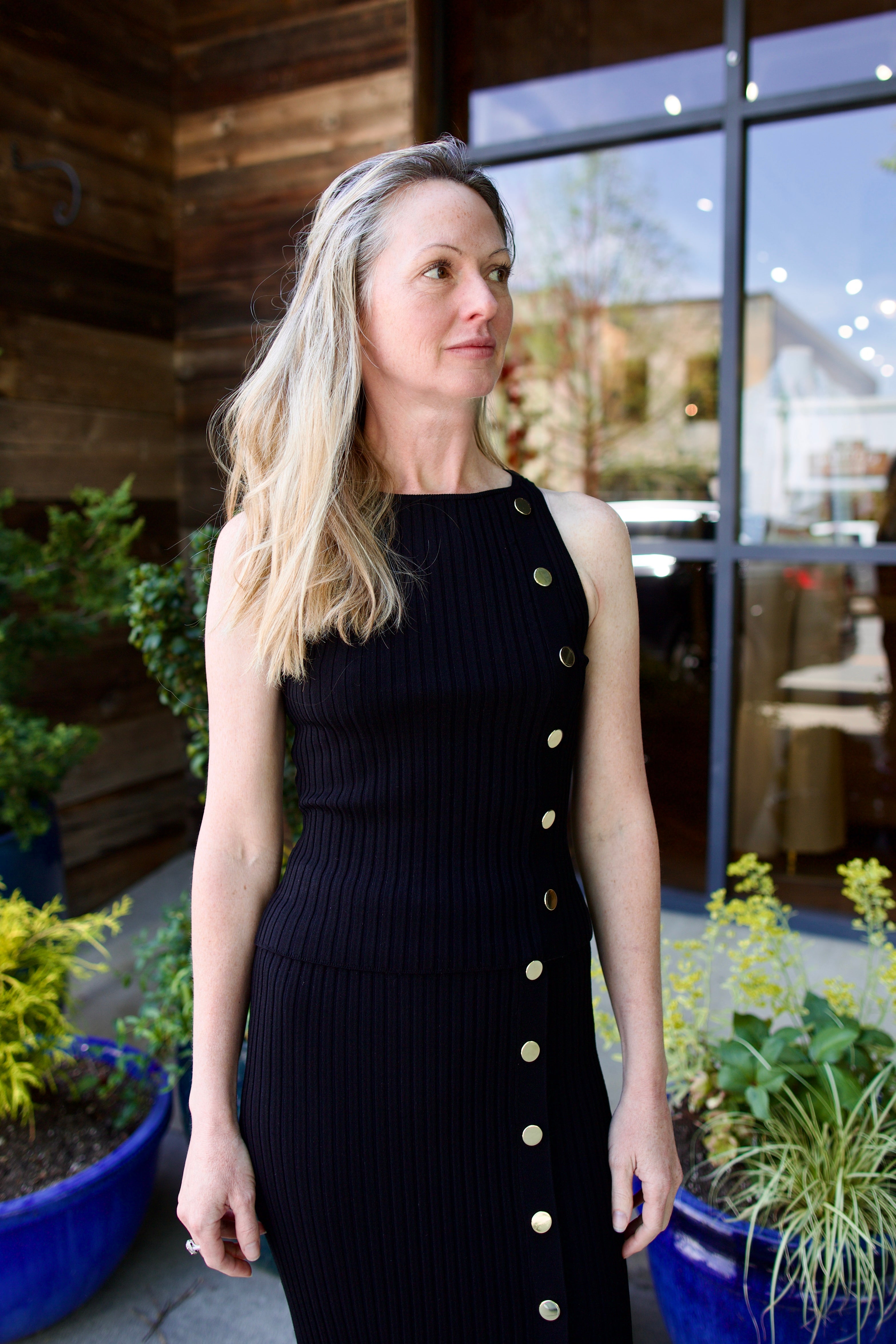 woman wearing Veronica Beard black knit Tanner Skirt with gold buttons leg vent comfy stretchy ribbed texture