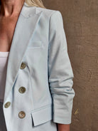 Mature woman wearing tailored Veronica Beard Tomi Dickey Jacket light blue ruched sleeves with button front