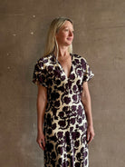 Mature woman wearing designer Veronica Beard V-Neck Redgrave Dress in Ecru Multi sheath maxi with a rich purple floral print Elongating, occasion-ready 
