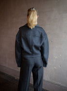 Image featuring a woman wearing the Bless jacket by Vanessa Bruno with an asymmetrical zipper, full sleeve and a slightly cropped fit in dark grey.