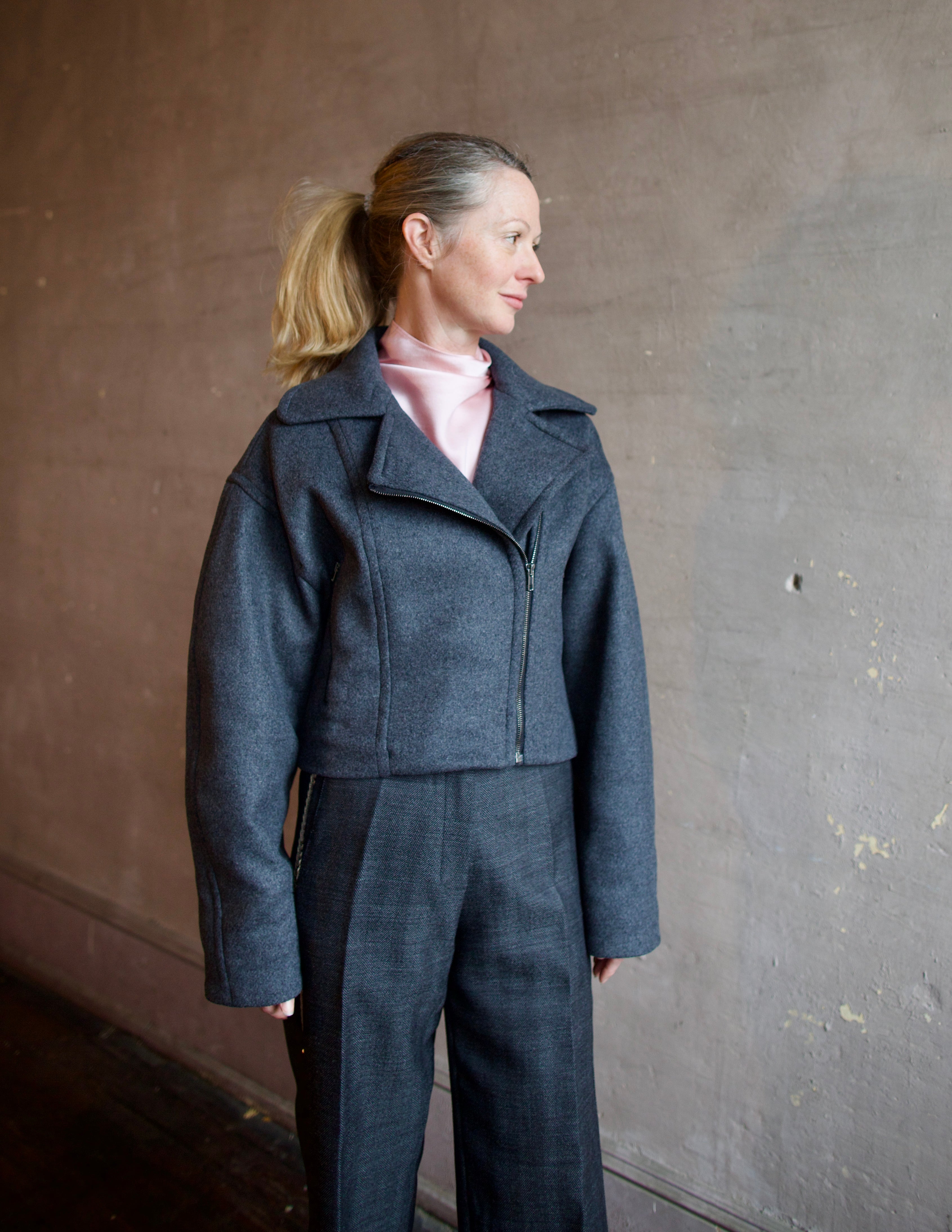 Image featuring a woman wearing the Bless jacket by Vanessa Bruno with an asymmetrical zipper, full sleeve and a slightly cropped fit in dark grey.